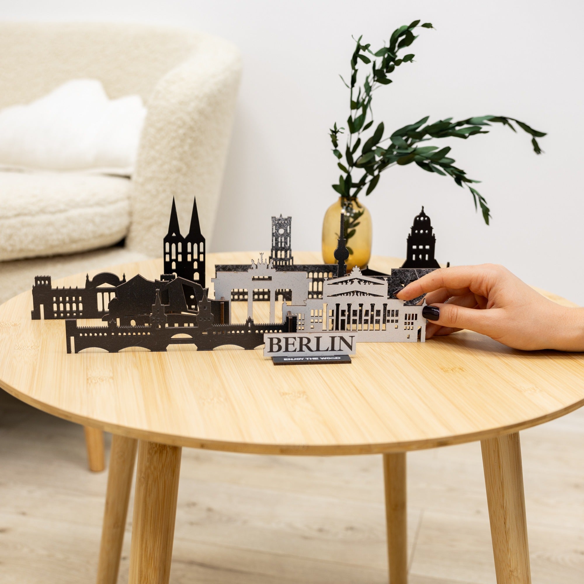 Model of Berlin skyline on a wooden table with a hand holding a smaller version.