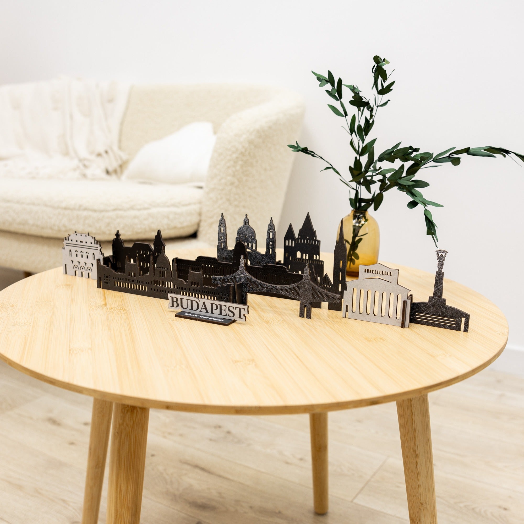 Decorative items including a 'Budapest' model on a wooden table with a white sofa in the background.