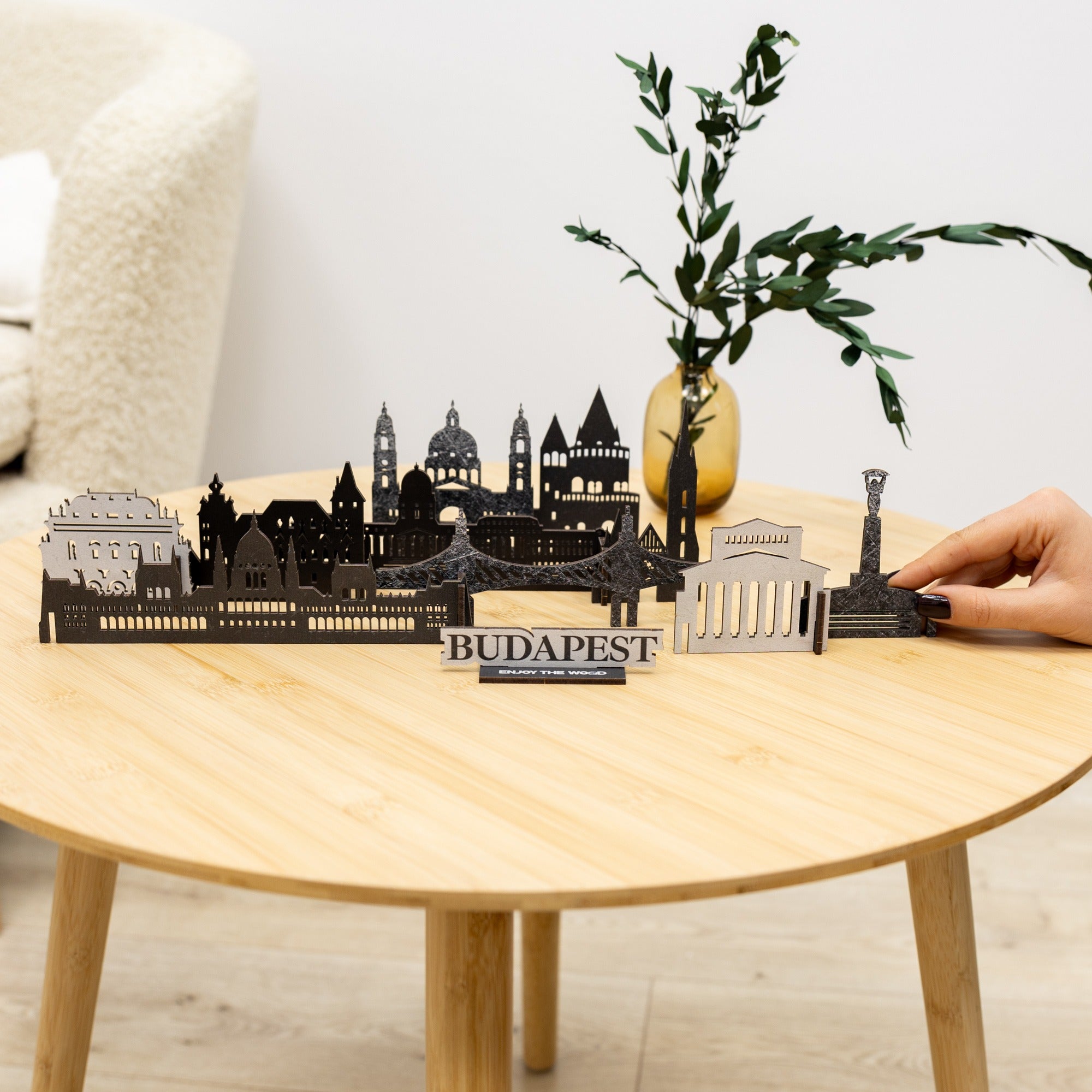 Model of Budapest skyline on a wooden table with a hand interacting with it.