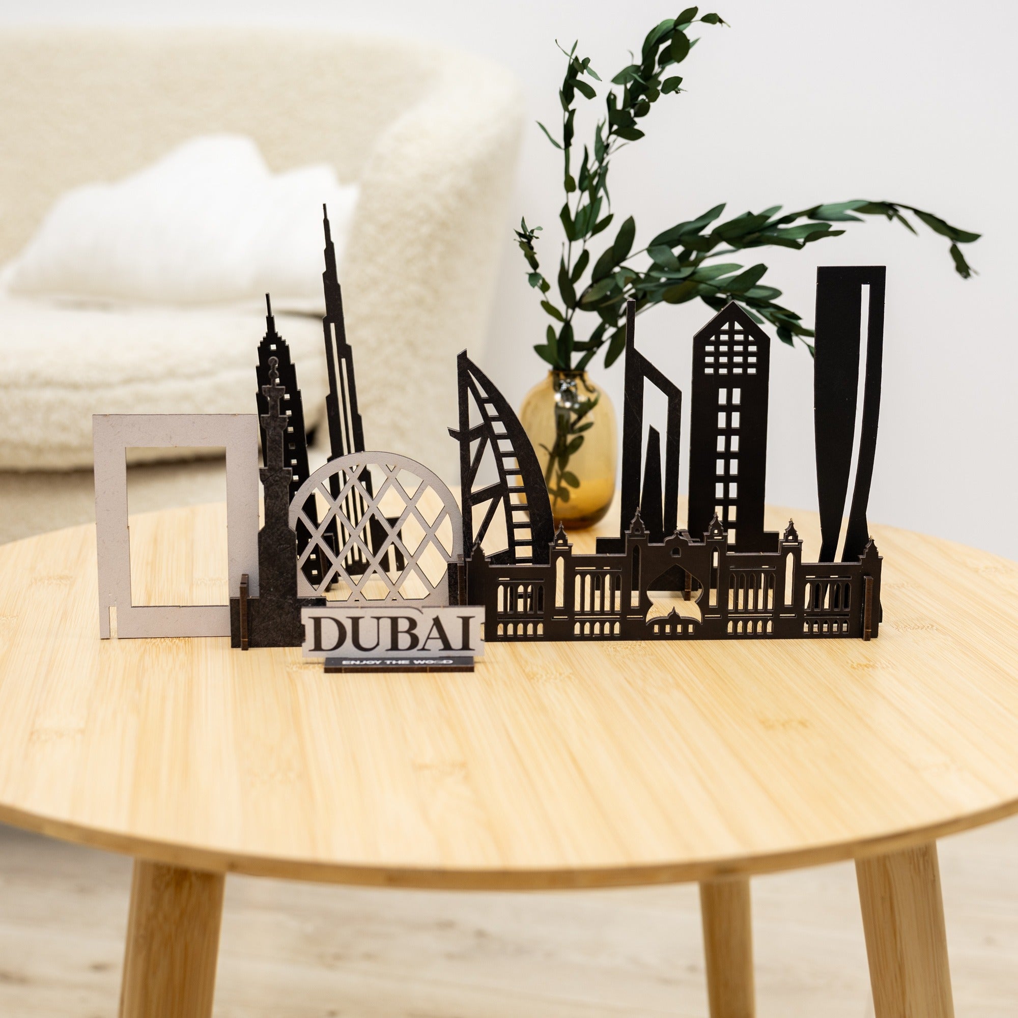 Black metal Dubai skyline model on a wooden table with a plant in the background