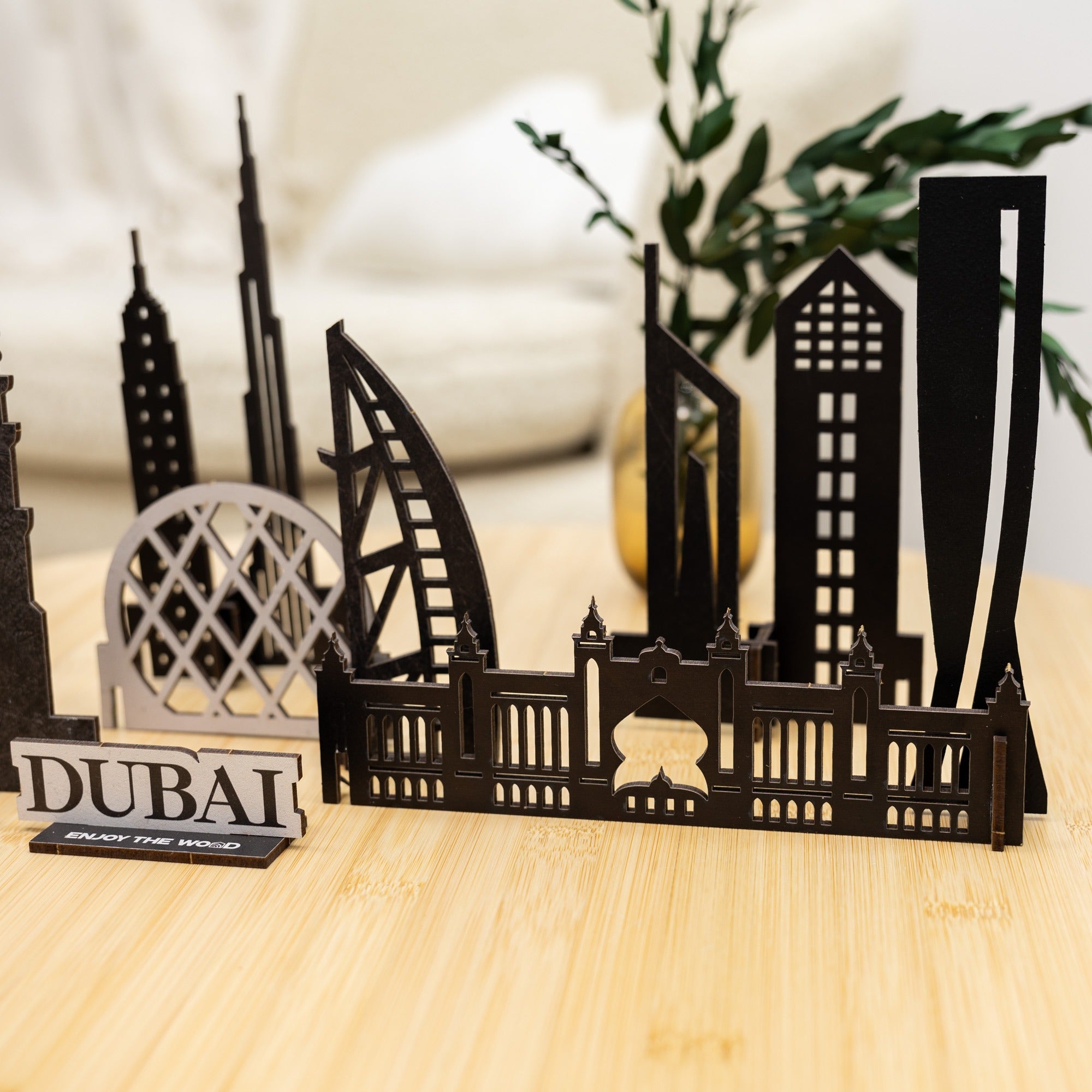 Black metal model of Dubai skyline on a wooden surface with a plant in the background