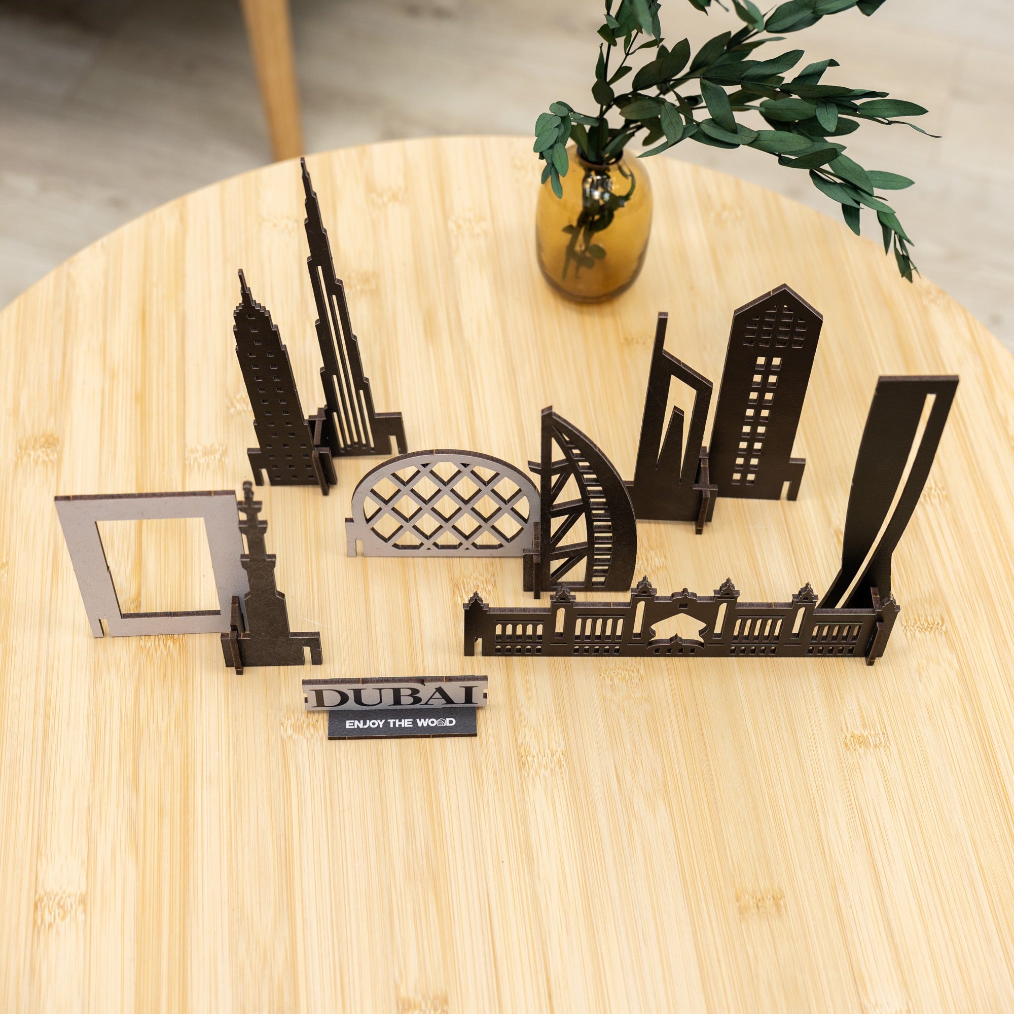 Metallic Dubai skyline model on a wooden surface with a plant in the background