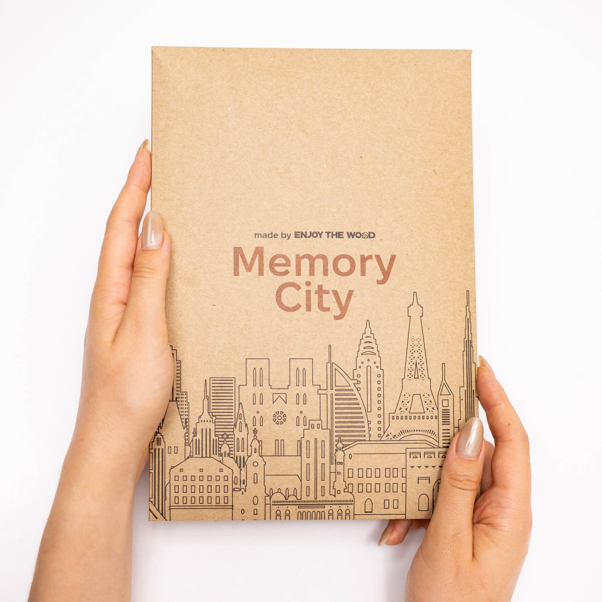 Brown notebook titled 'Memory City' held by hands on a white background