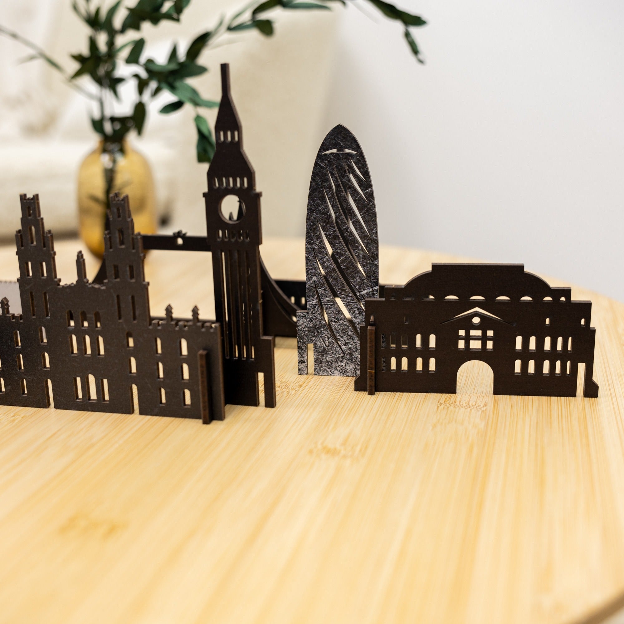 Black metal cityscape model on a wooden surface with a blurred background