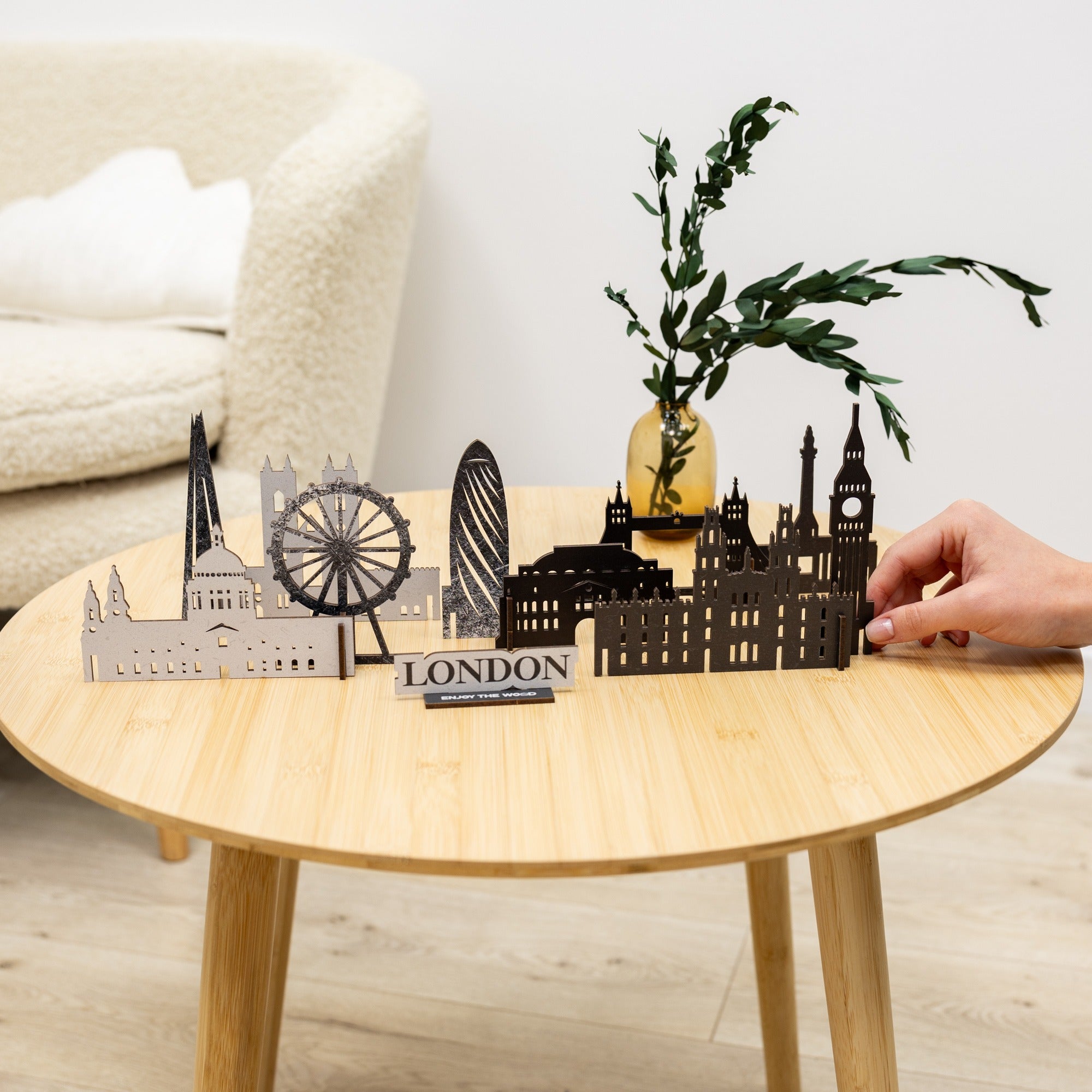 Model of London skyline on a wooden table with a hand reaching out