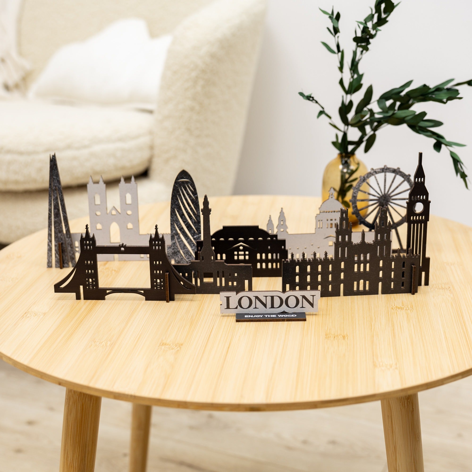 Metal London skyline model on a wooden table with a plant in the background