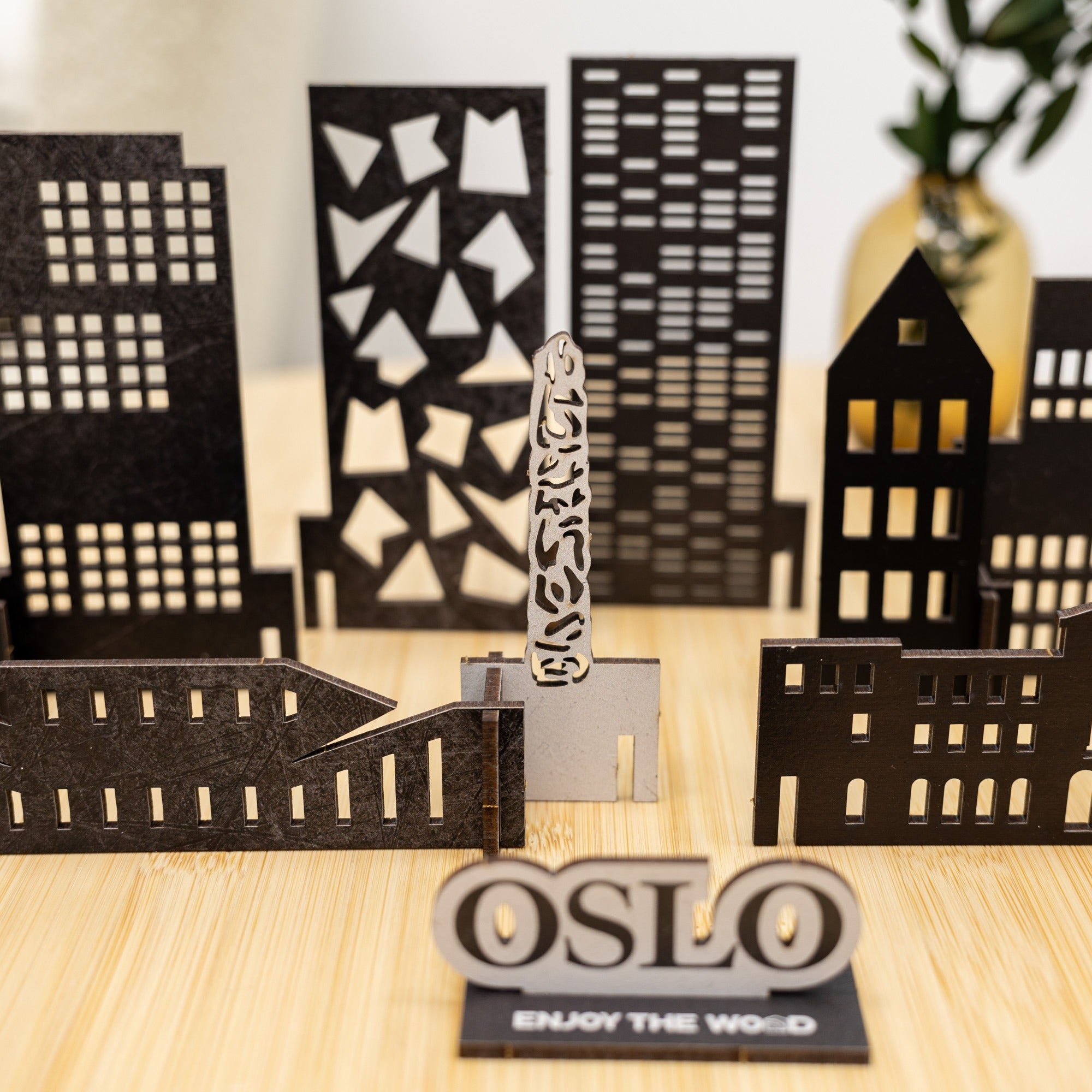 Black cut-out cityscape with 'OSLO' sign on a wooden surface
