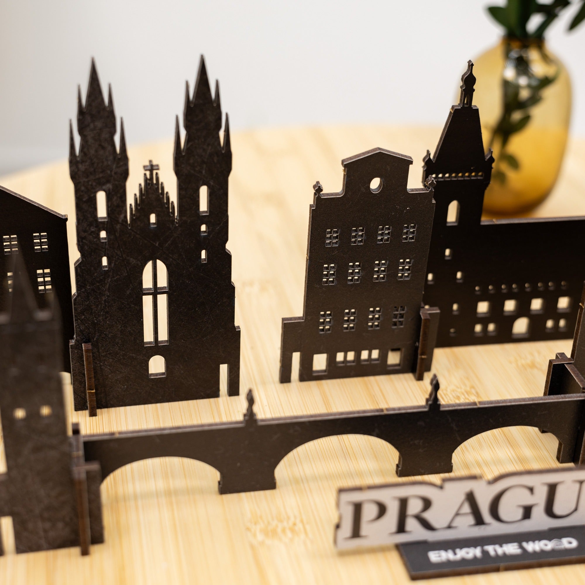 Black metal model of Prague skyline on a wooden base with 'Prague' sign.