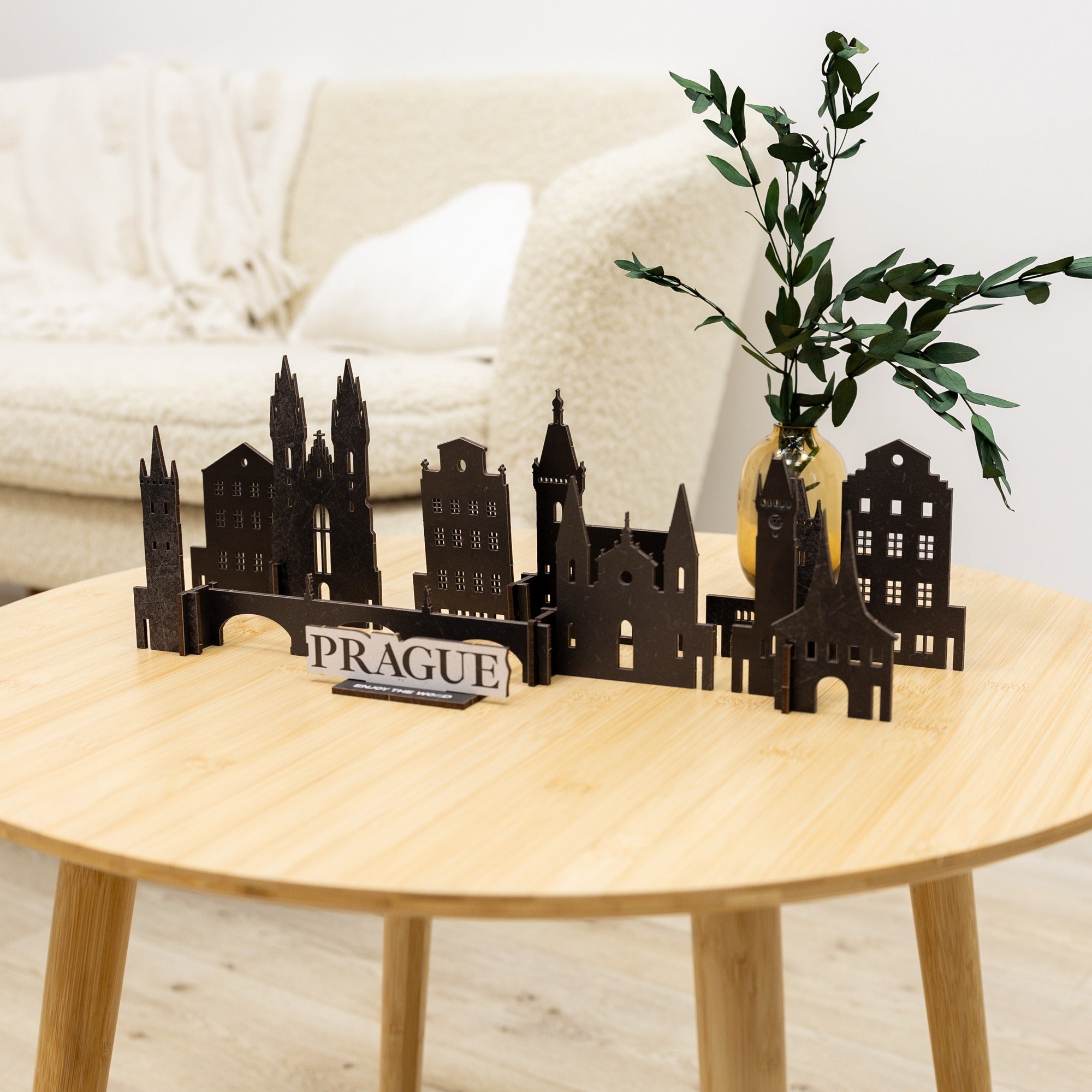 Model of Prague's architecture on a wooden table with a vase and plant in the background.