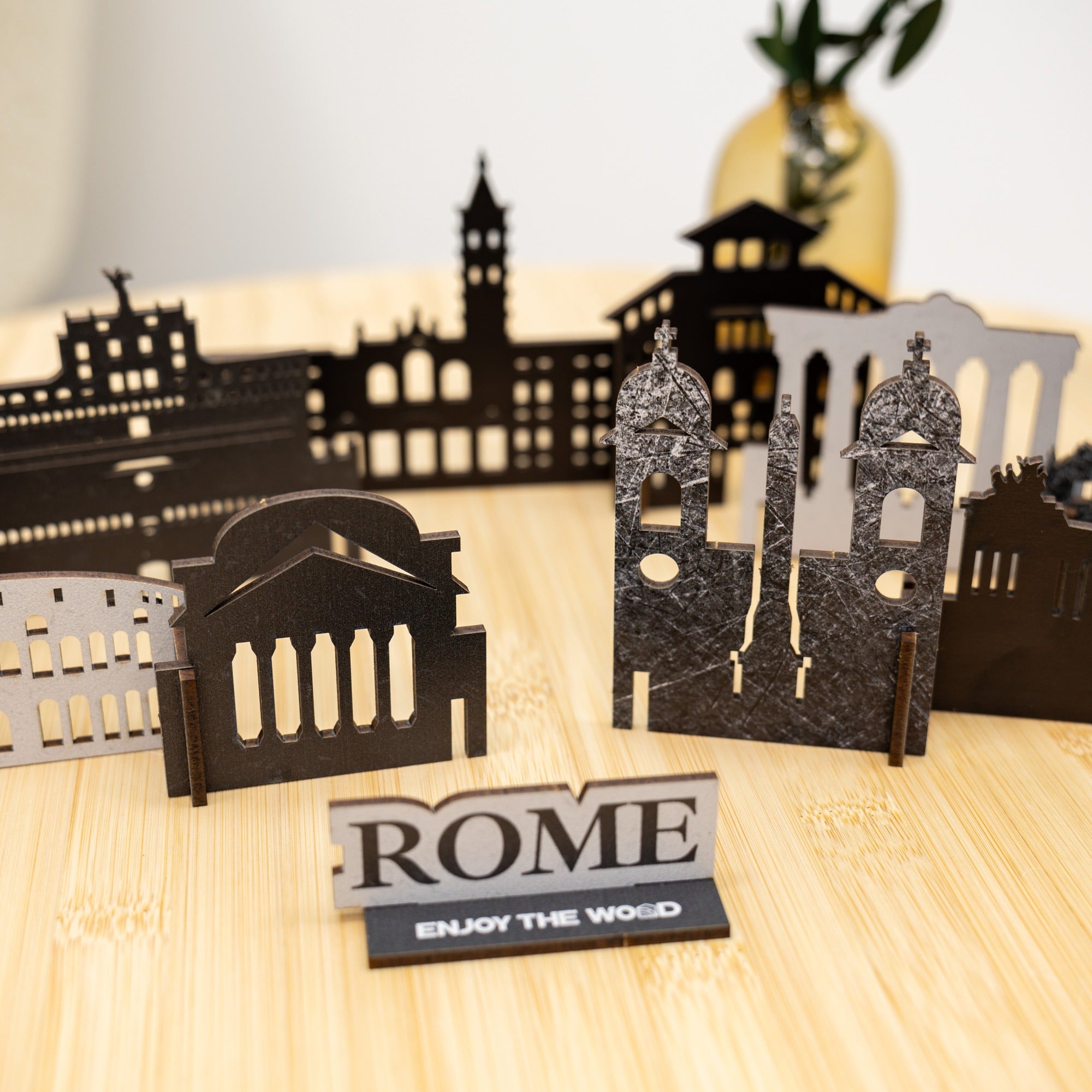 Wooden cutout models of famous Roman buildings with 'ROME' sign on a wooden surface