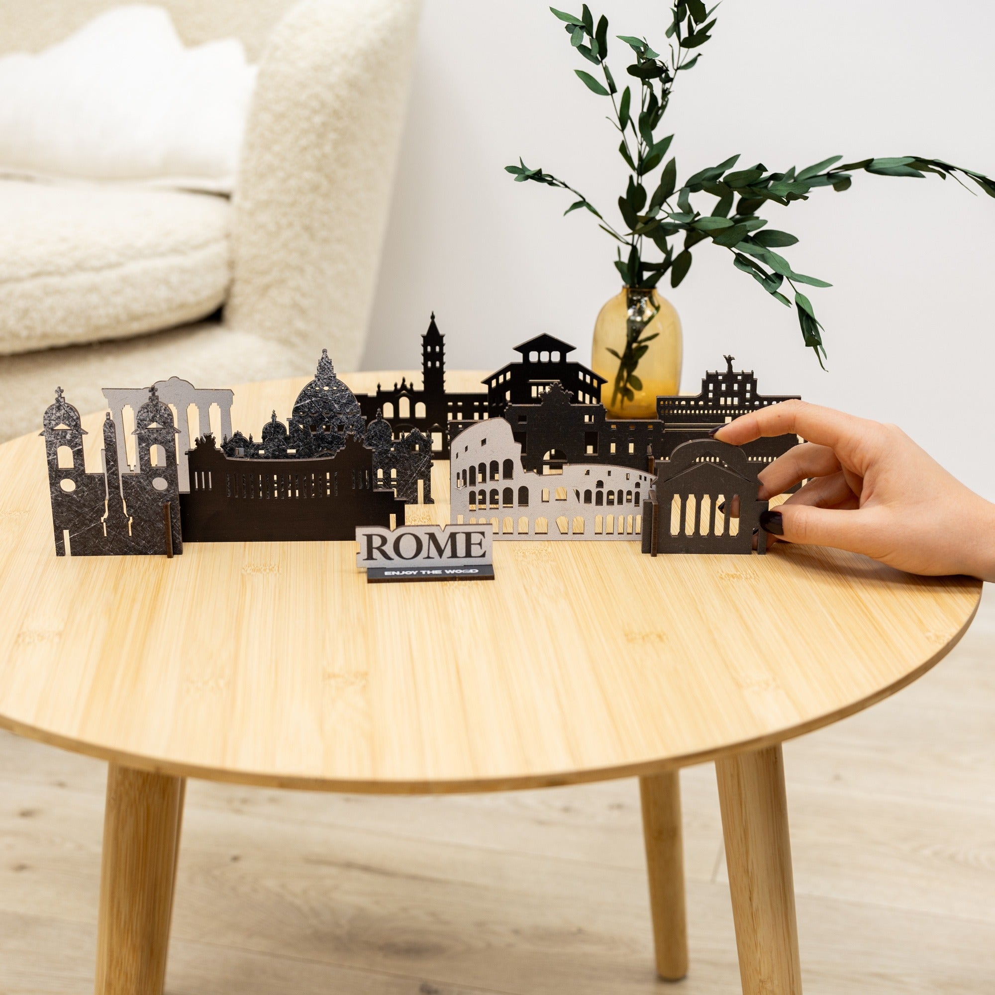 3D cityscape model of Rome on a wooden table with a hand interacting with it.