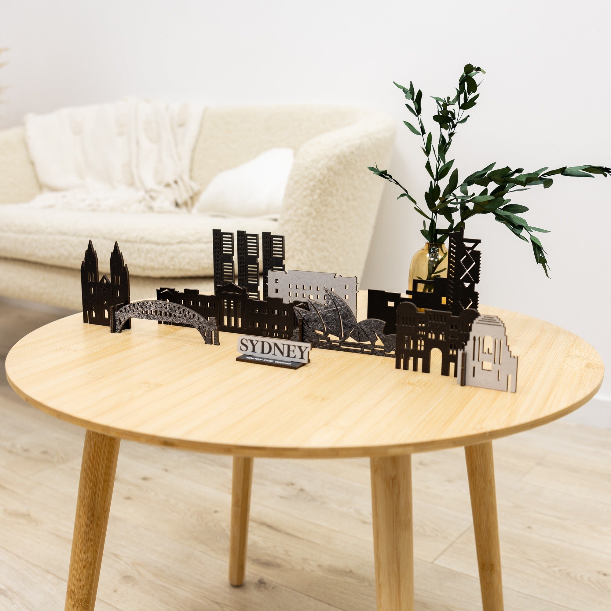 Model of Sydney skyline on a wooden table with a white couch and plant in the background