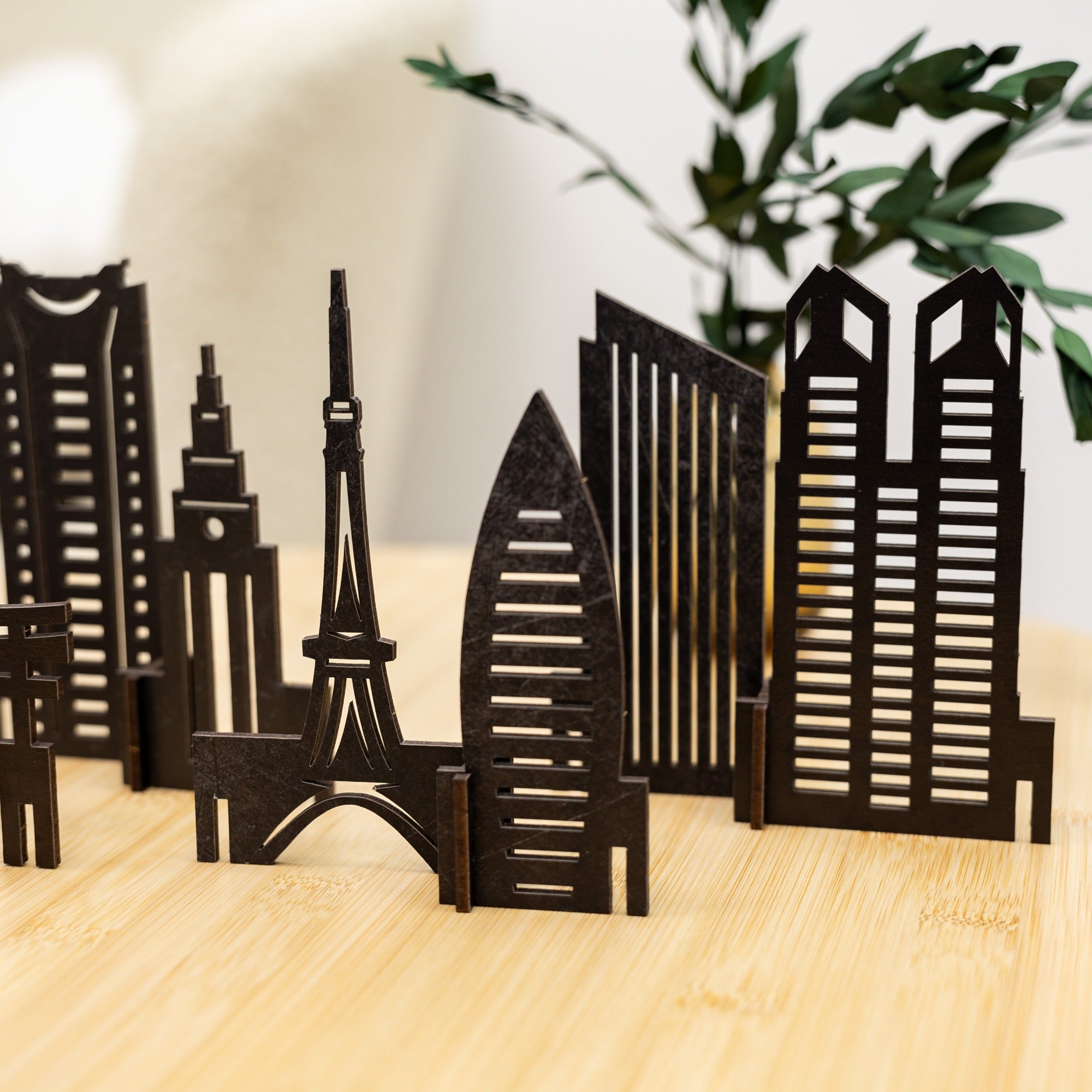 Black city skyline model on a wooden surface with a blurred plant in the background