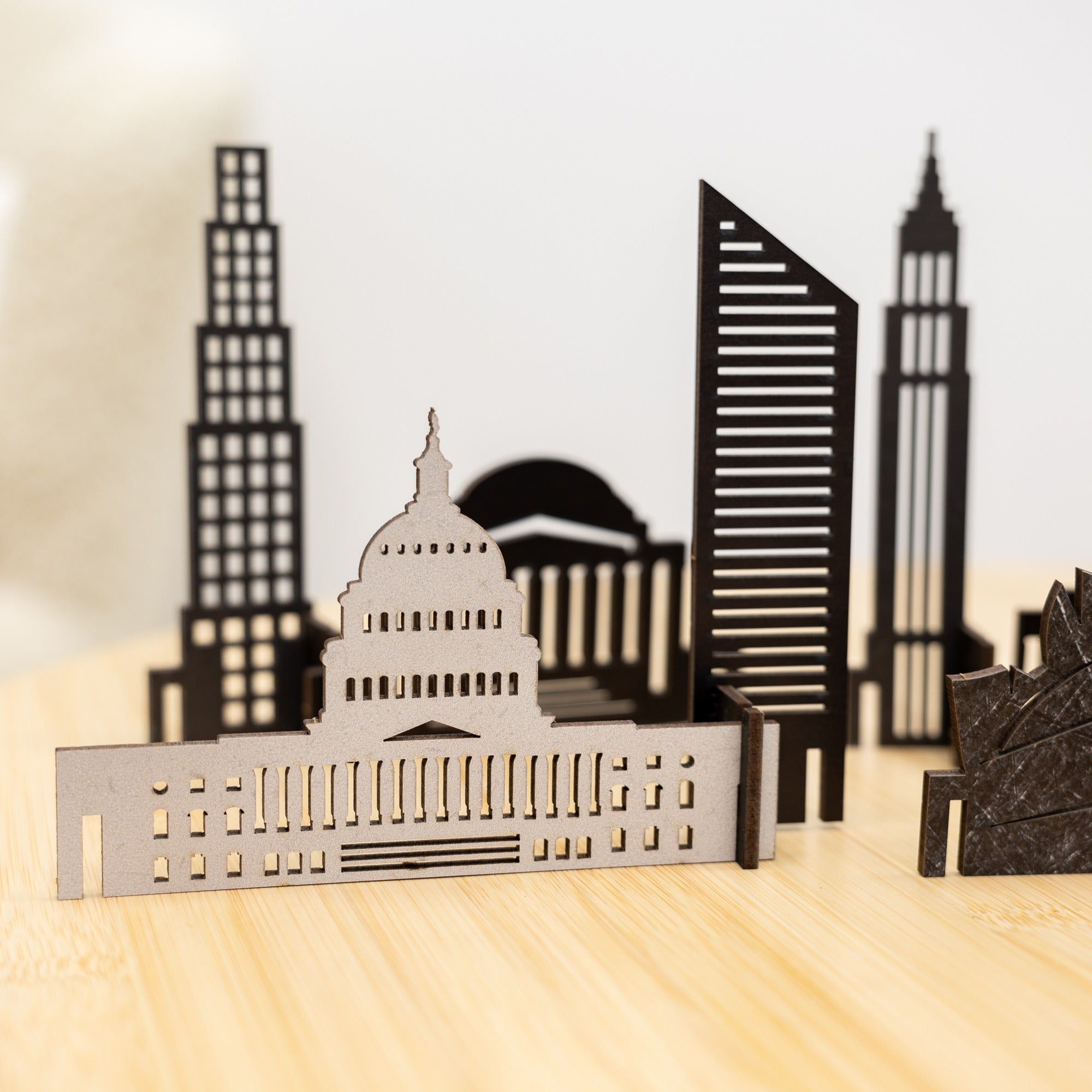 Model of a city skyline with a prominent building on a wooden surface