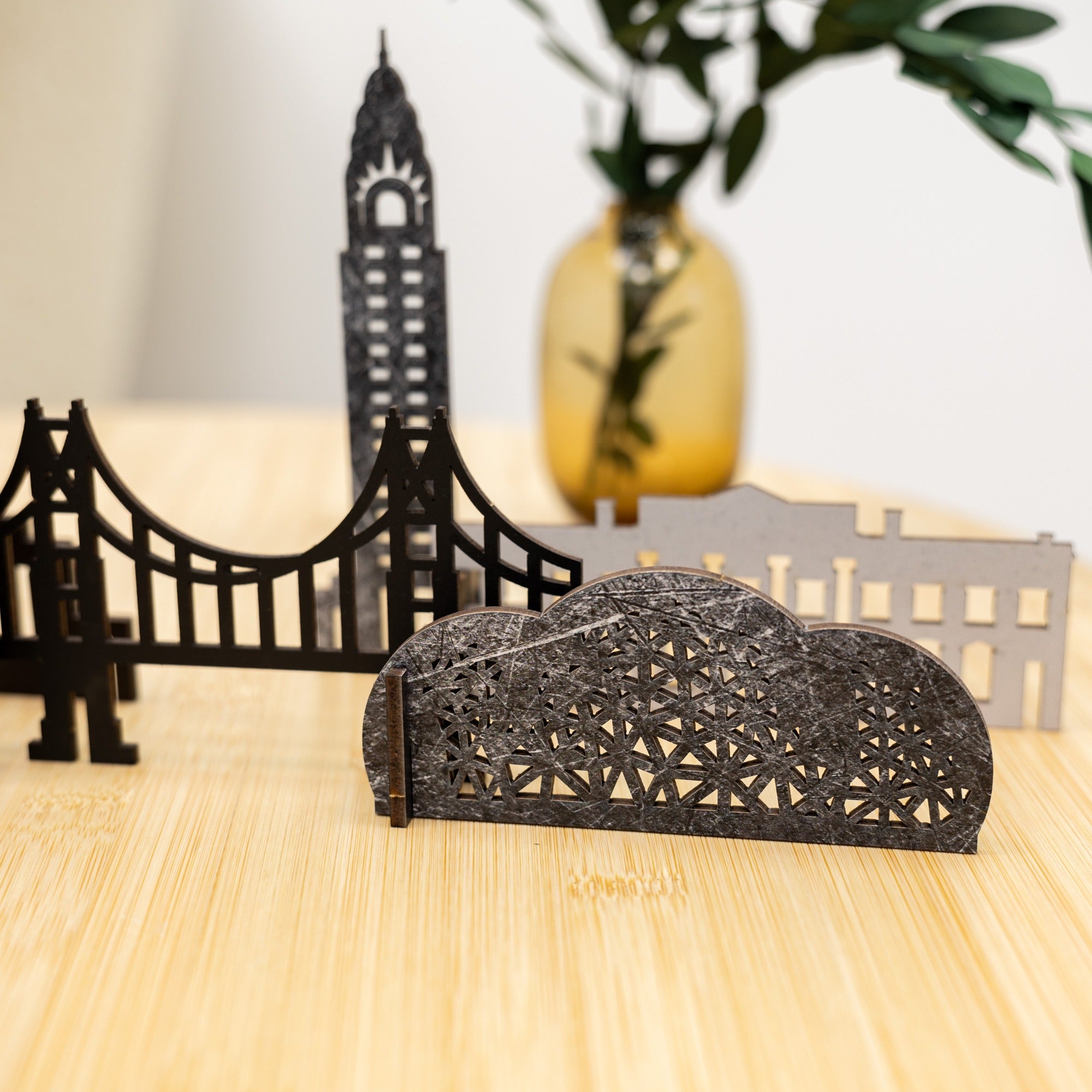 Decorative metal models of a bridge and cityscape on a wooden surface.