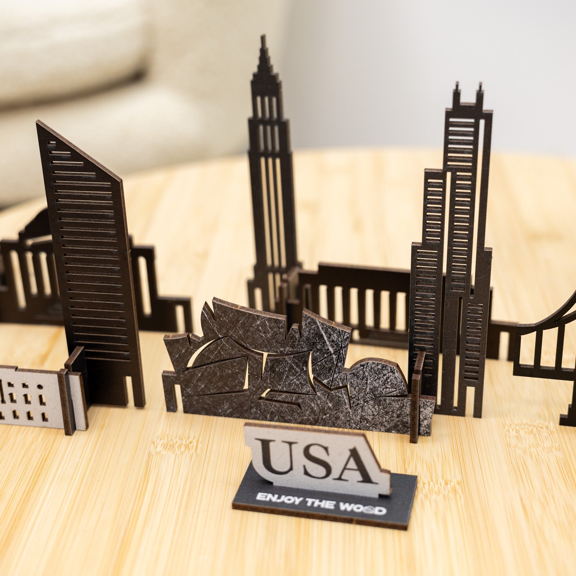 Model of a city skyline with 'USA' and 'Enjoy the Wood' text on a wooden surface.