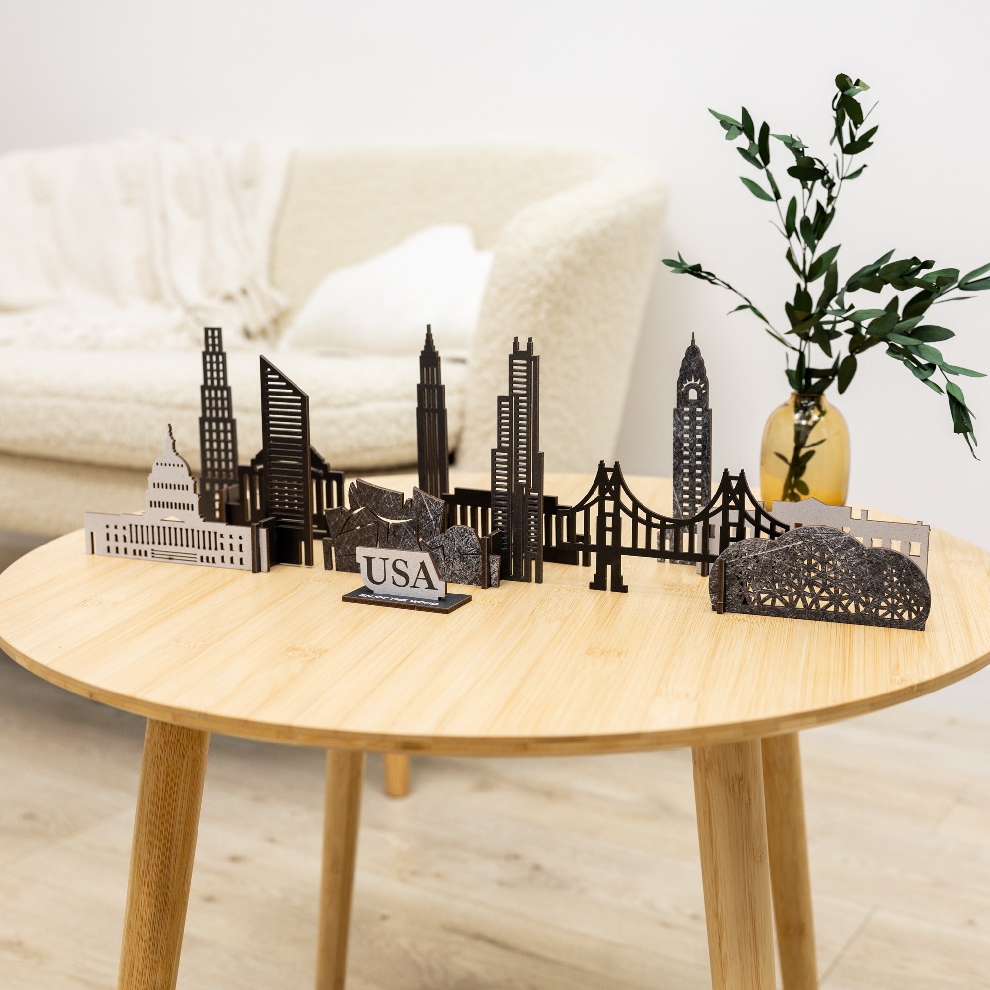 Black metal cityscape model on a wooden table with a plant in the background