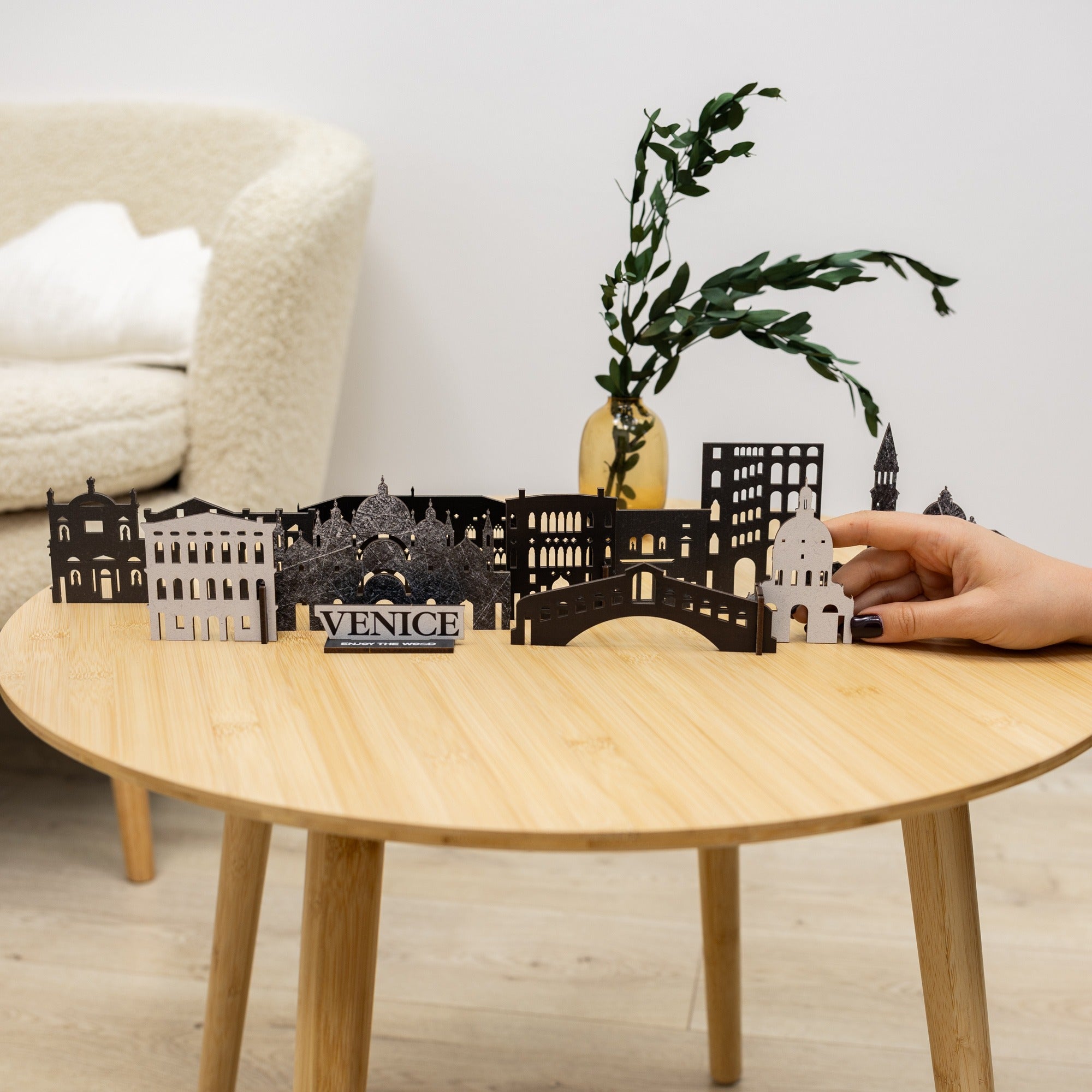 Venice skyline model on a wooden table with a hand holding one of the pieces.