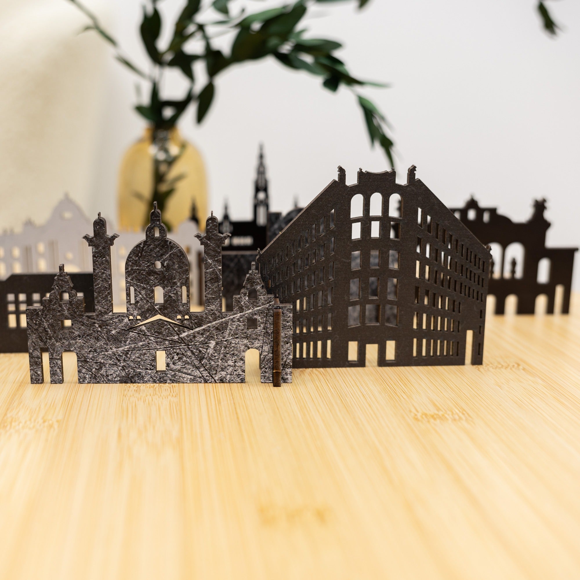 Black cut-out cityscape model on a wooden surface with blurred background