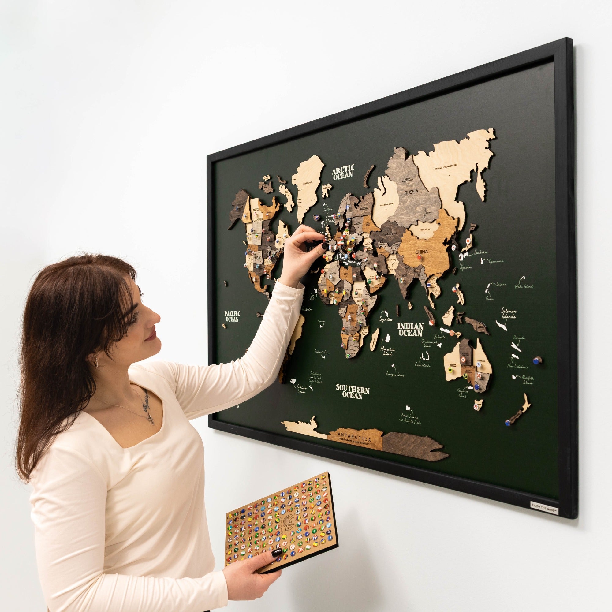 Woman interacting with a world map poster on a wall