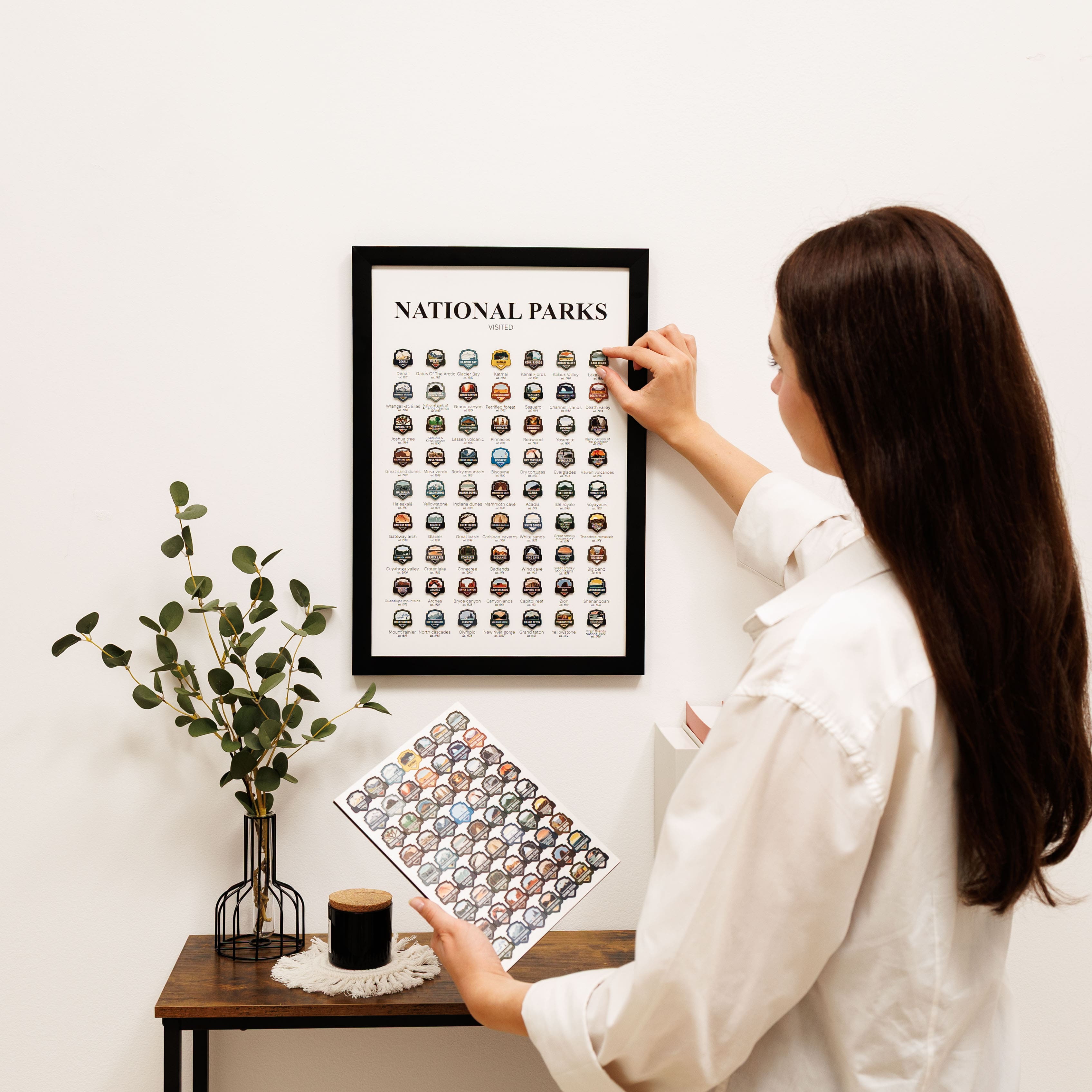Woman hanging a framed print of national parks on a wall