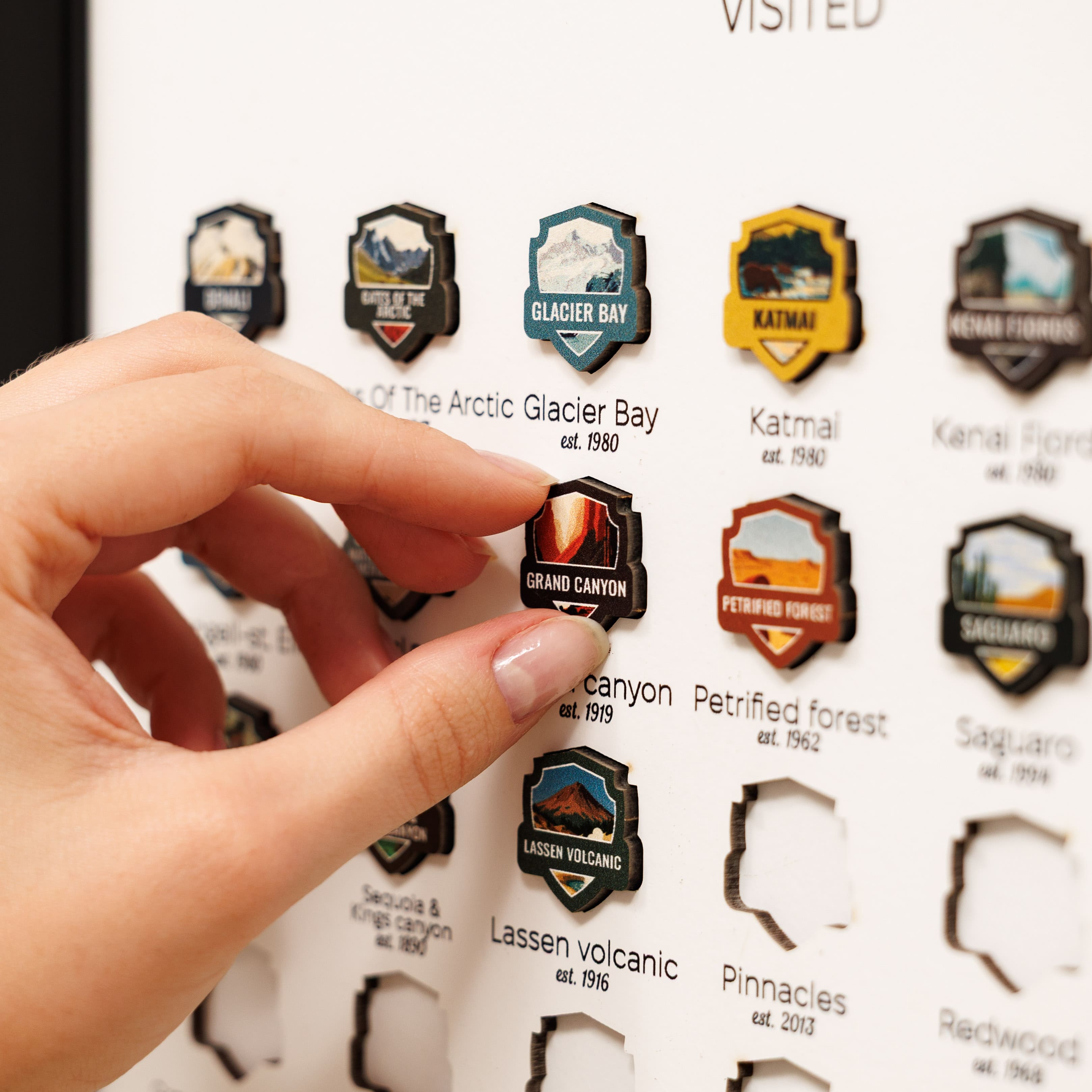 Hand interacting with a collection of travel stickers on a paper background