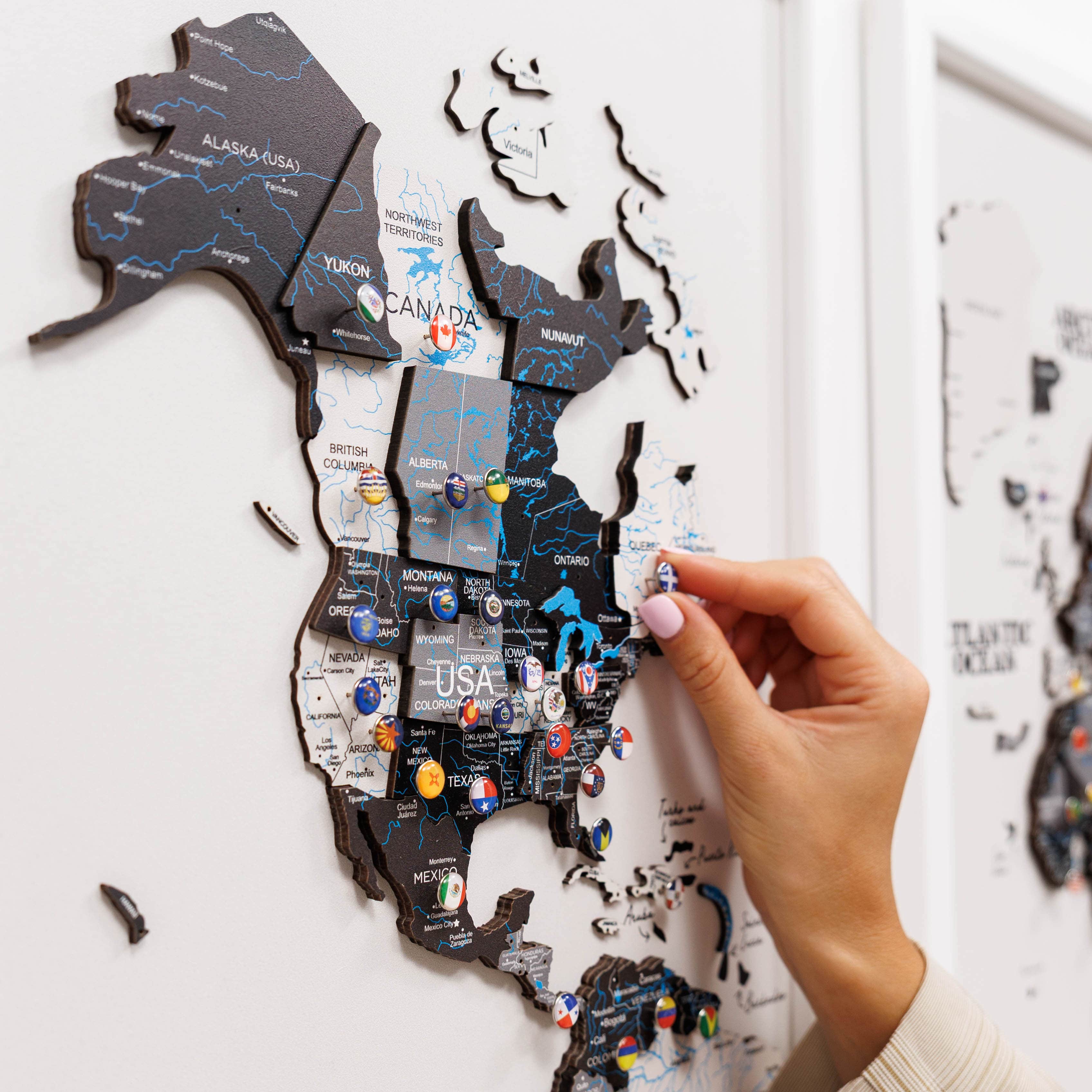 Hand placing a puzzle piece on a map of North America with pins marking locations.