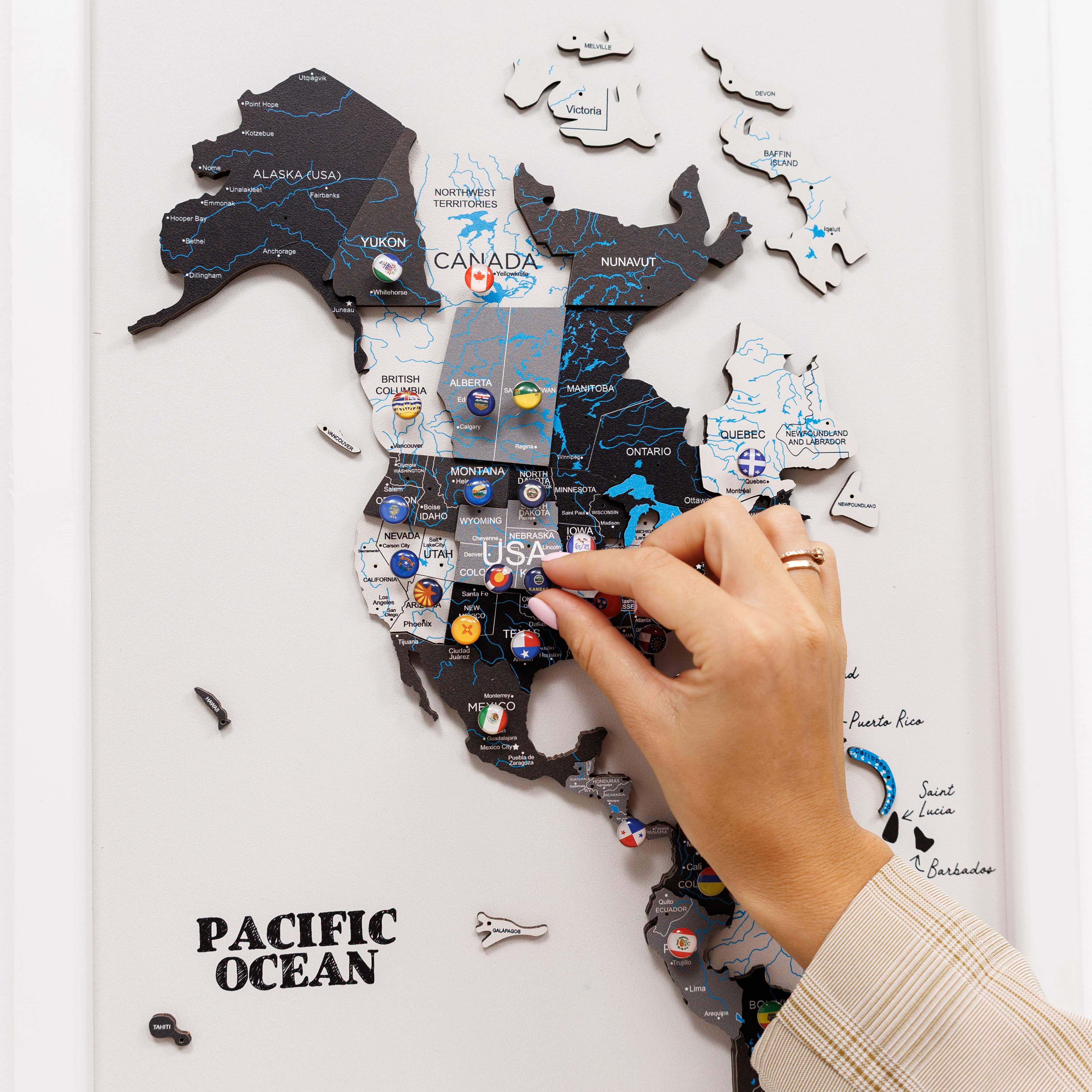 Map of North America with pins marking locations, being held by a hand.