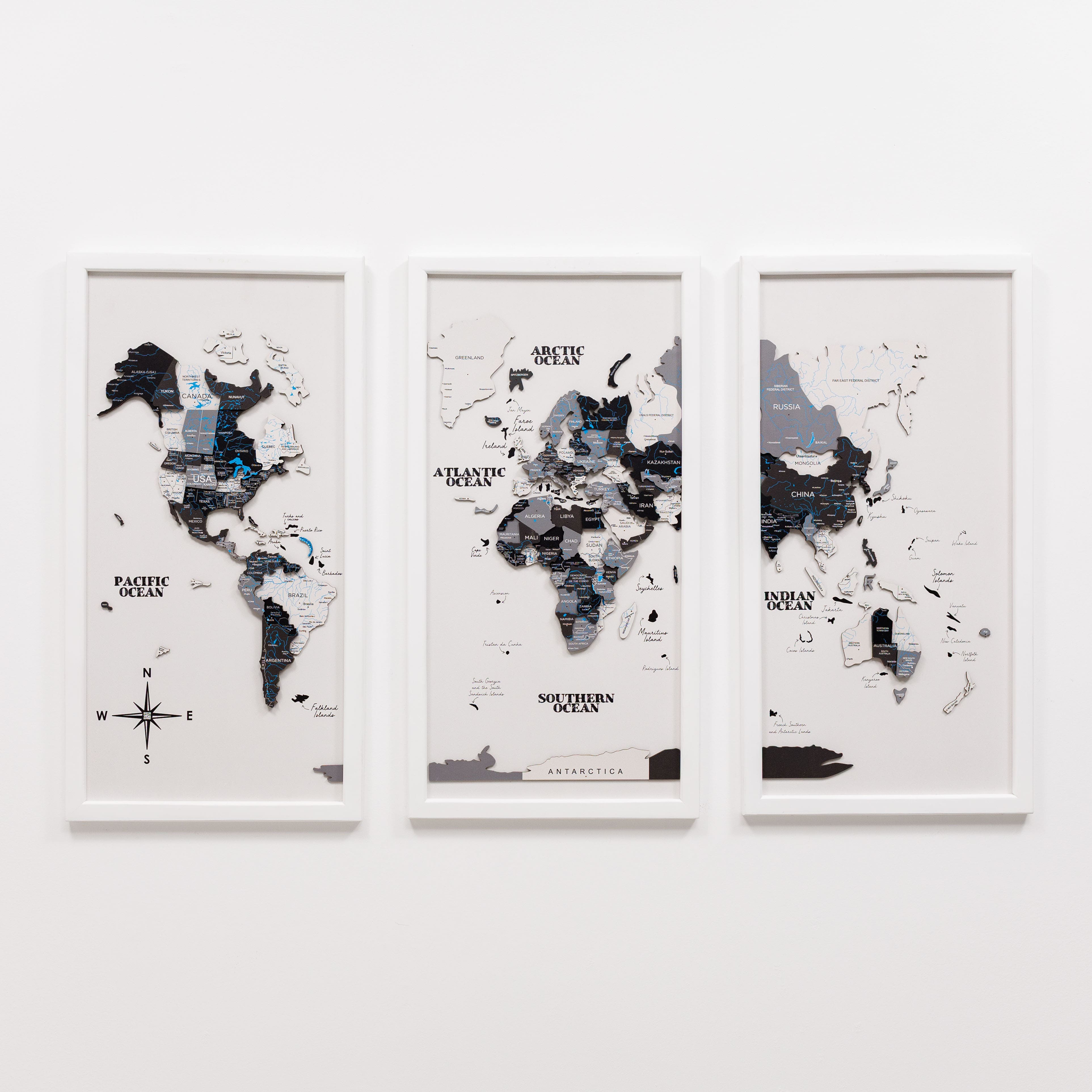 Three framed world maps on a white wall