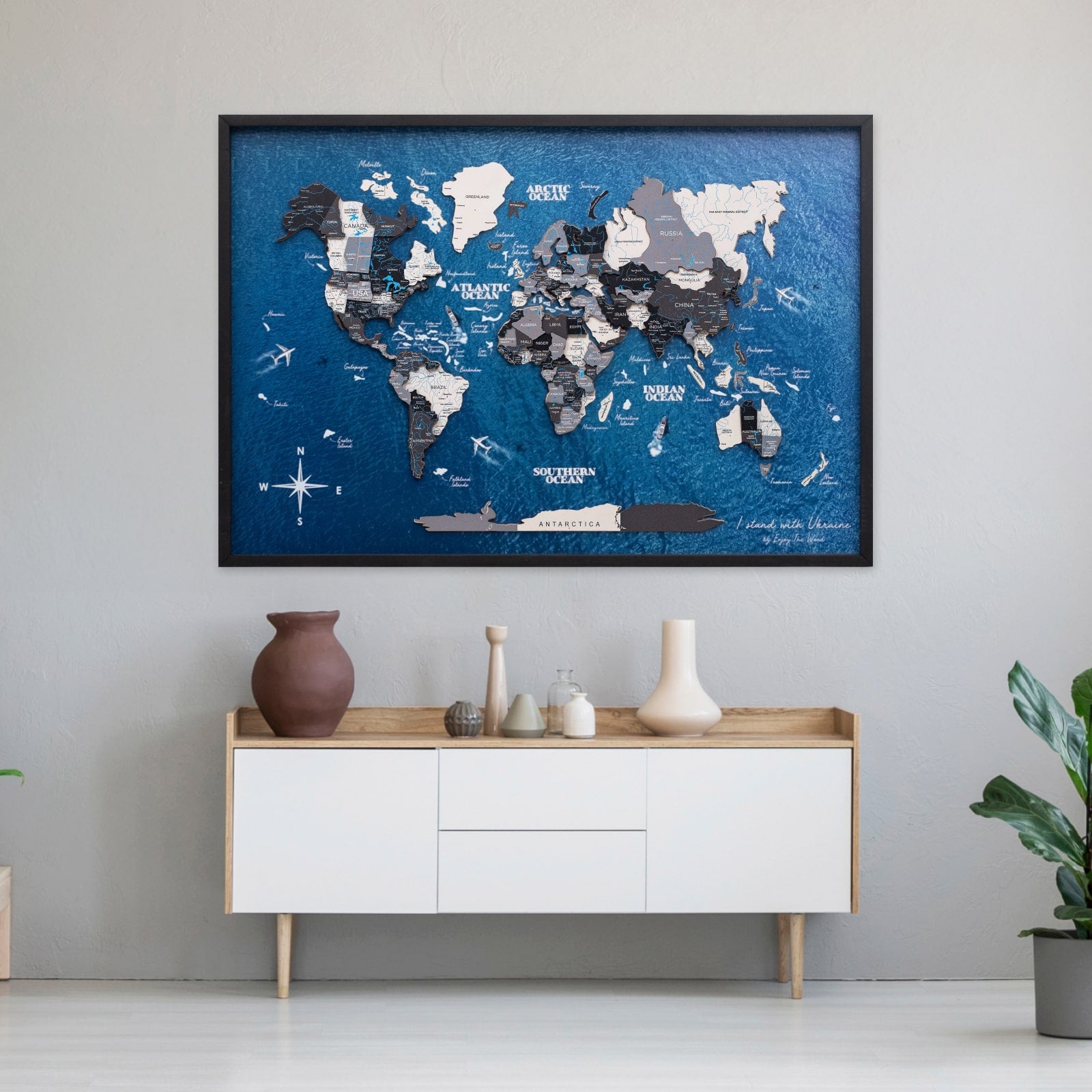 World map poster on a wall above a white cabinet with decorative items.