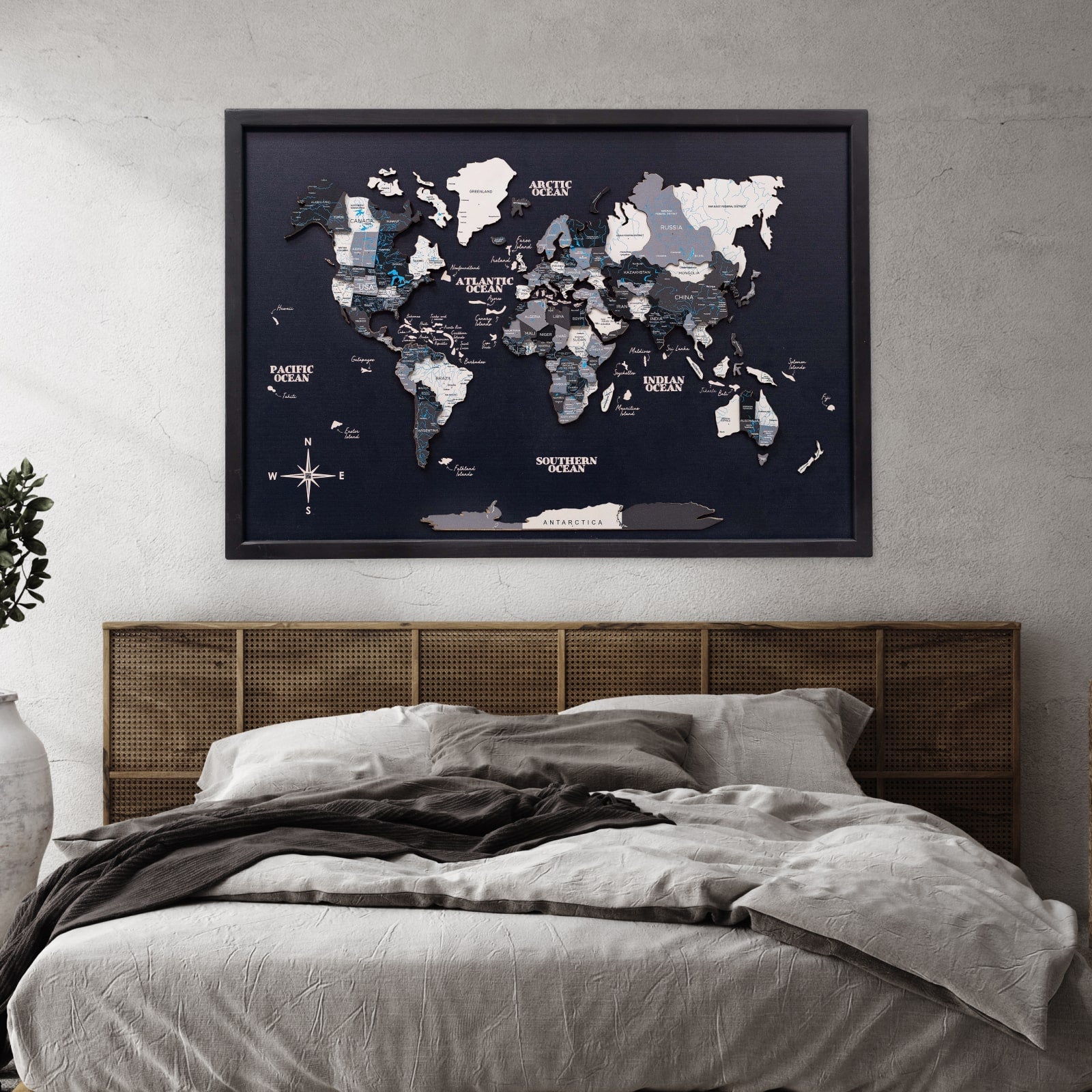 World map poster on a wall above a bed with wooden headboard