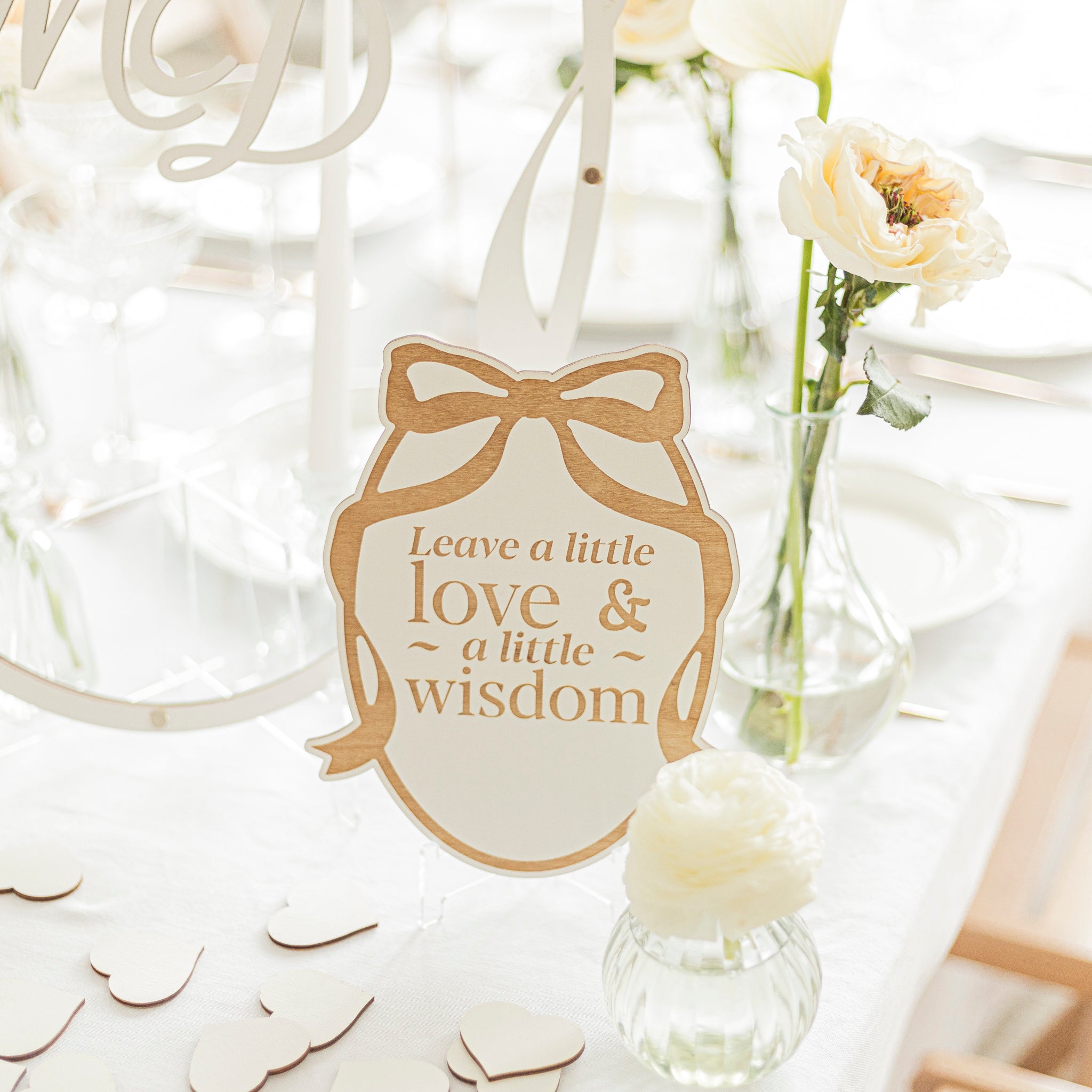 Decorative tag with 'Leave a little love & a little wisdom' text on a white background with flowers and confetti.