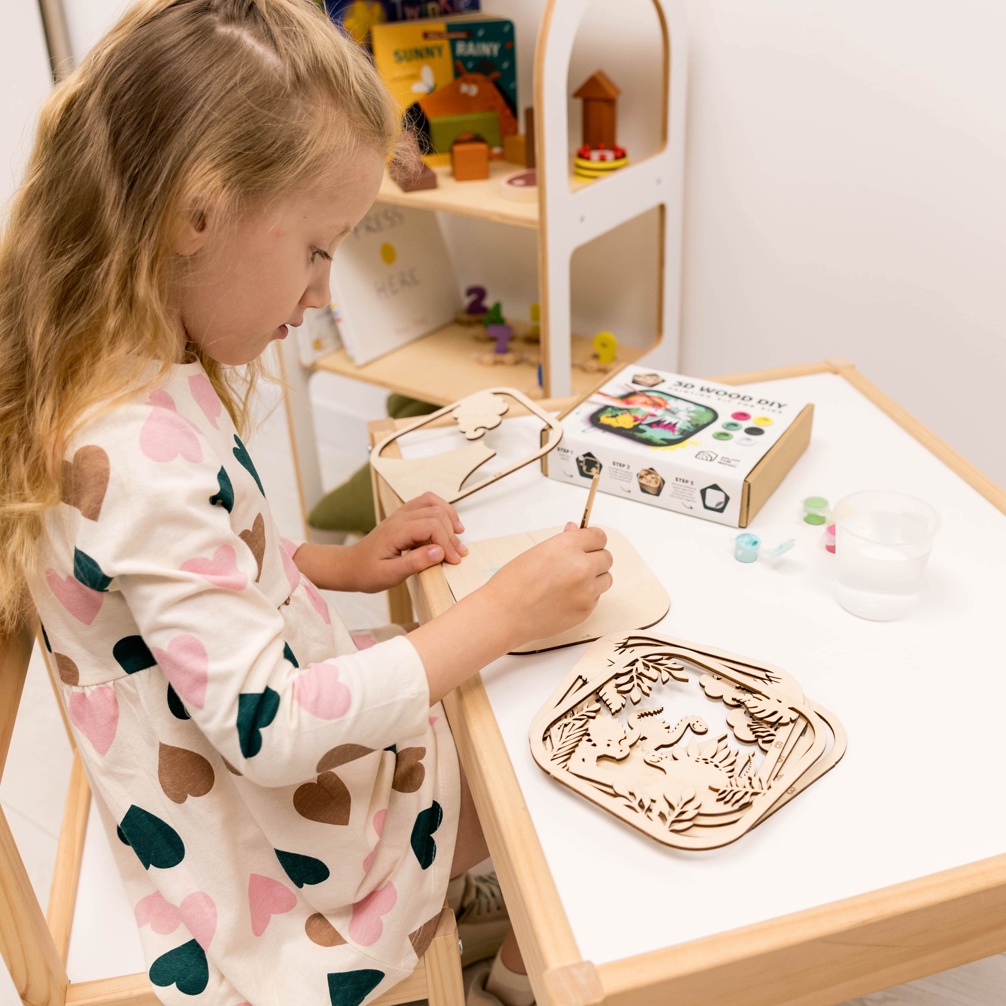 Child painting a wooden craft at a table with art supplies.