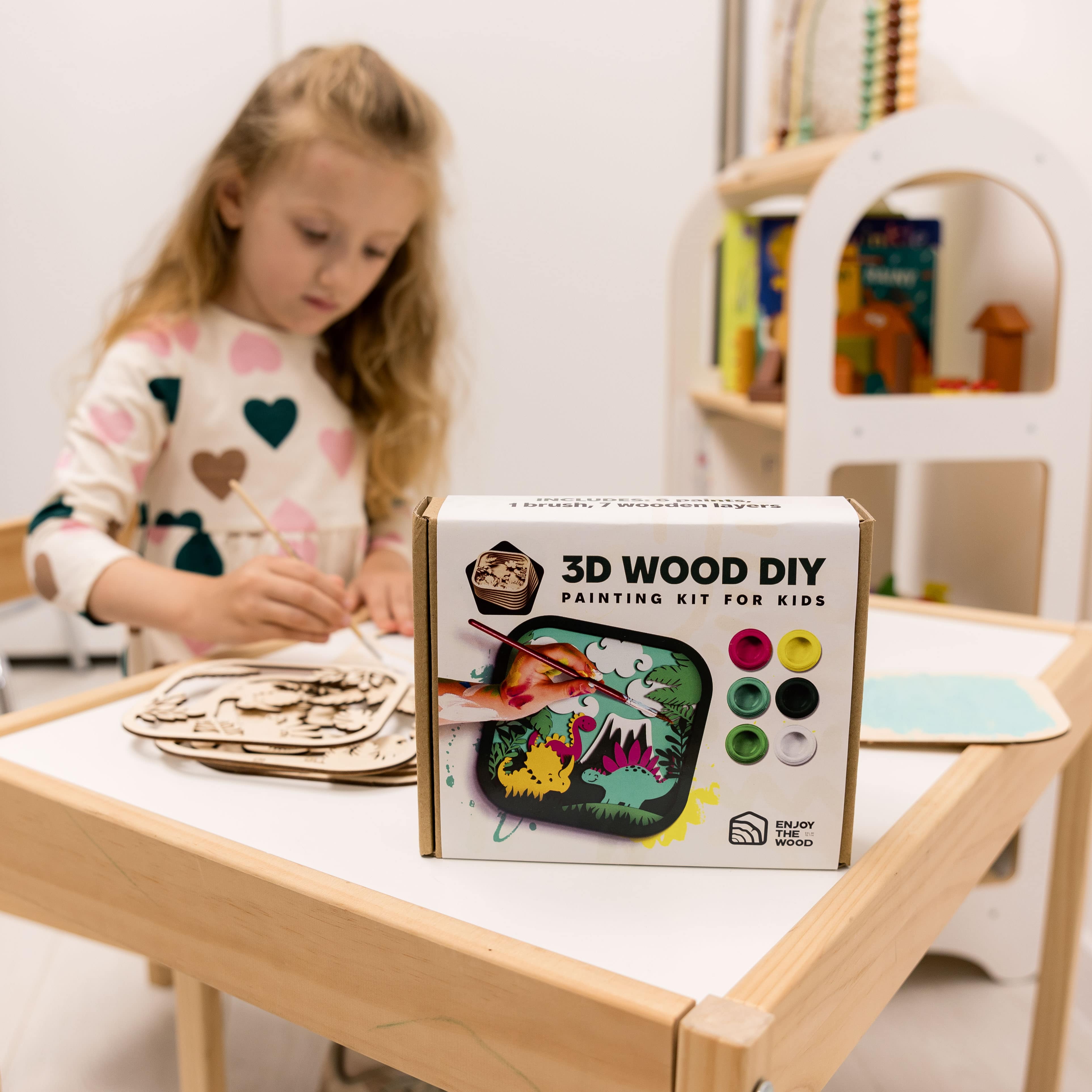 Child working on a craft project with a 3D wood DIY painting kit for kids on a table.