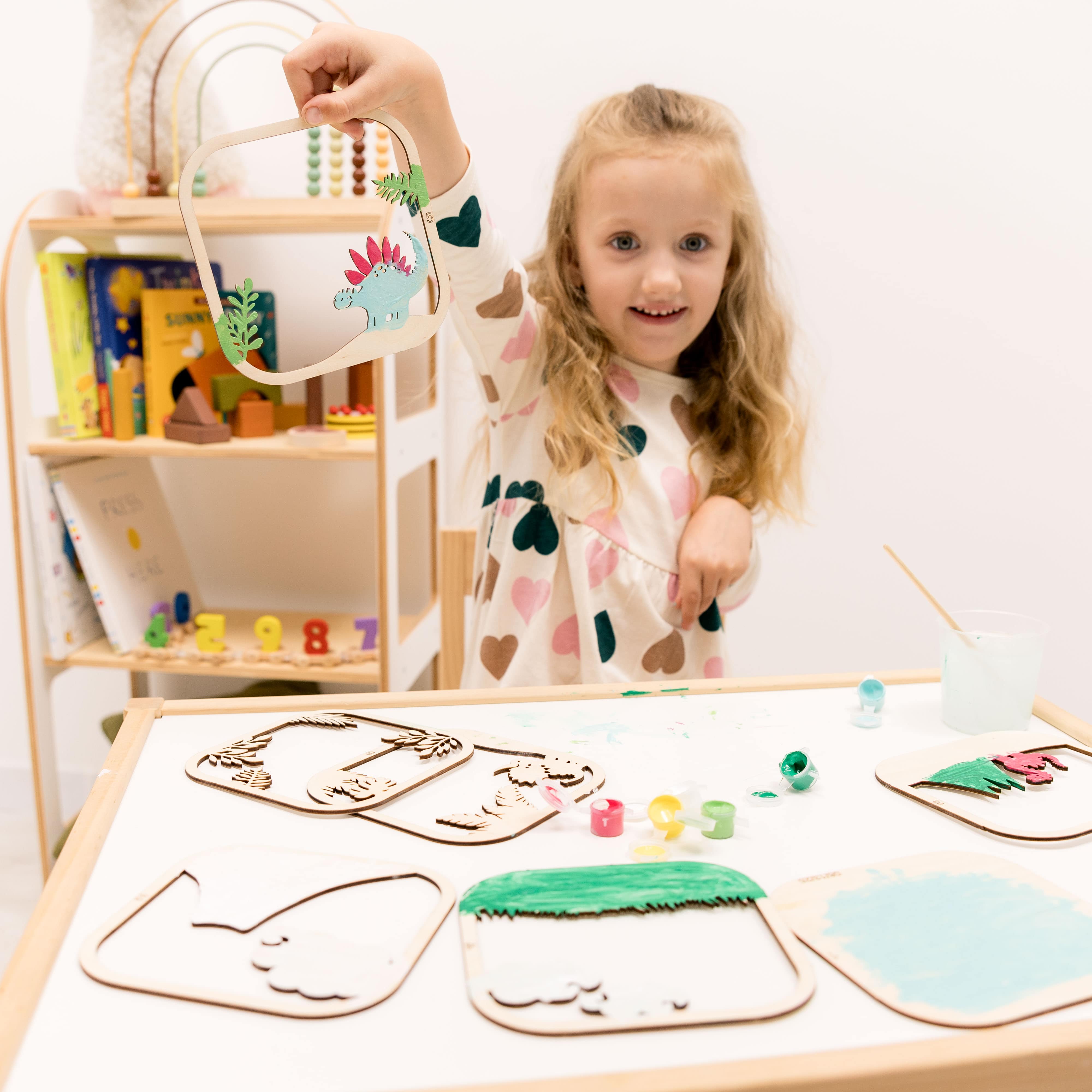 Child at a table with craft materials and a shelf in the background