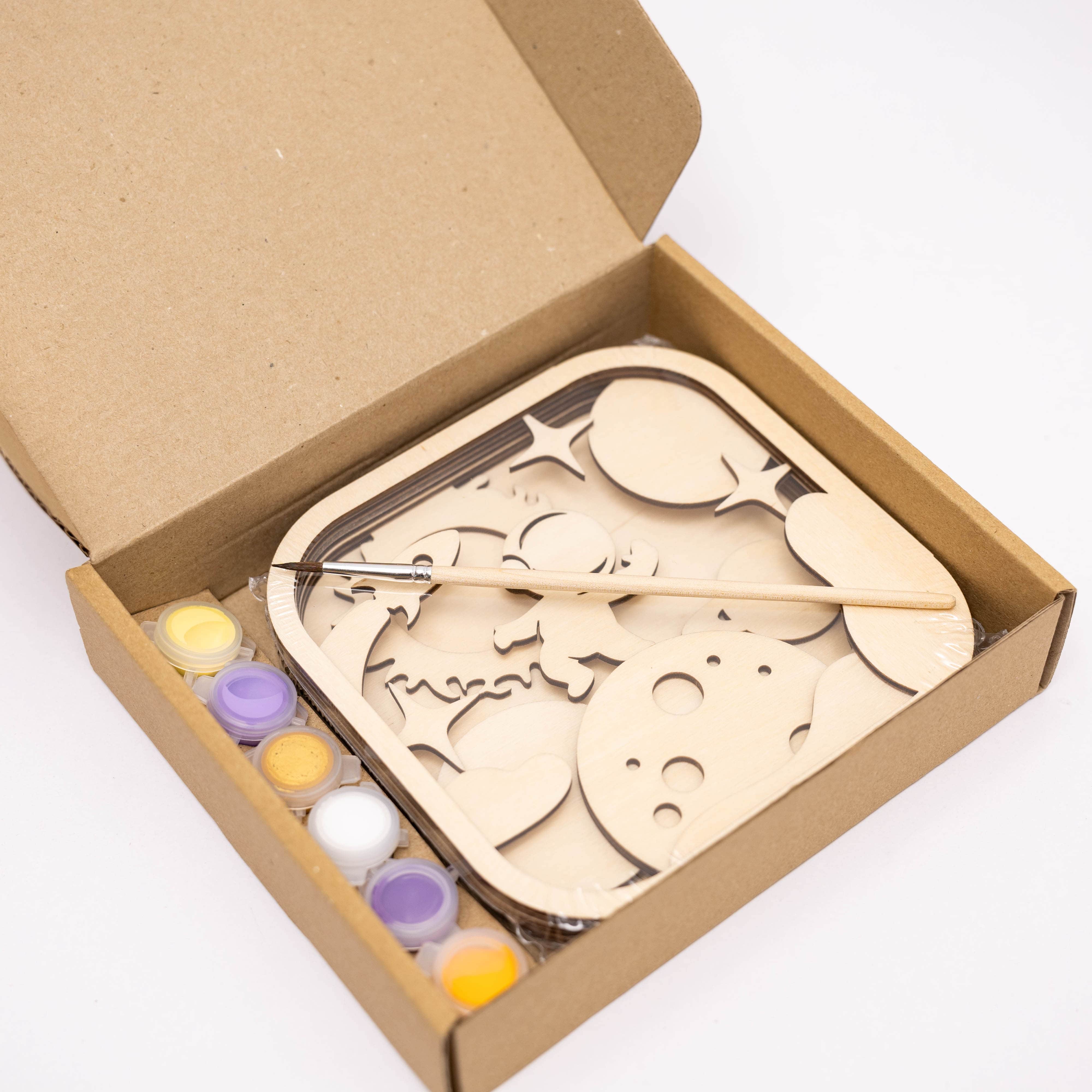Wooden puzzle with paint bottles in a cardboard box on a white background