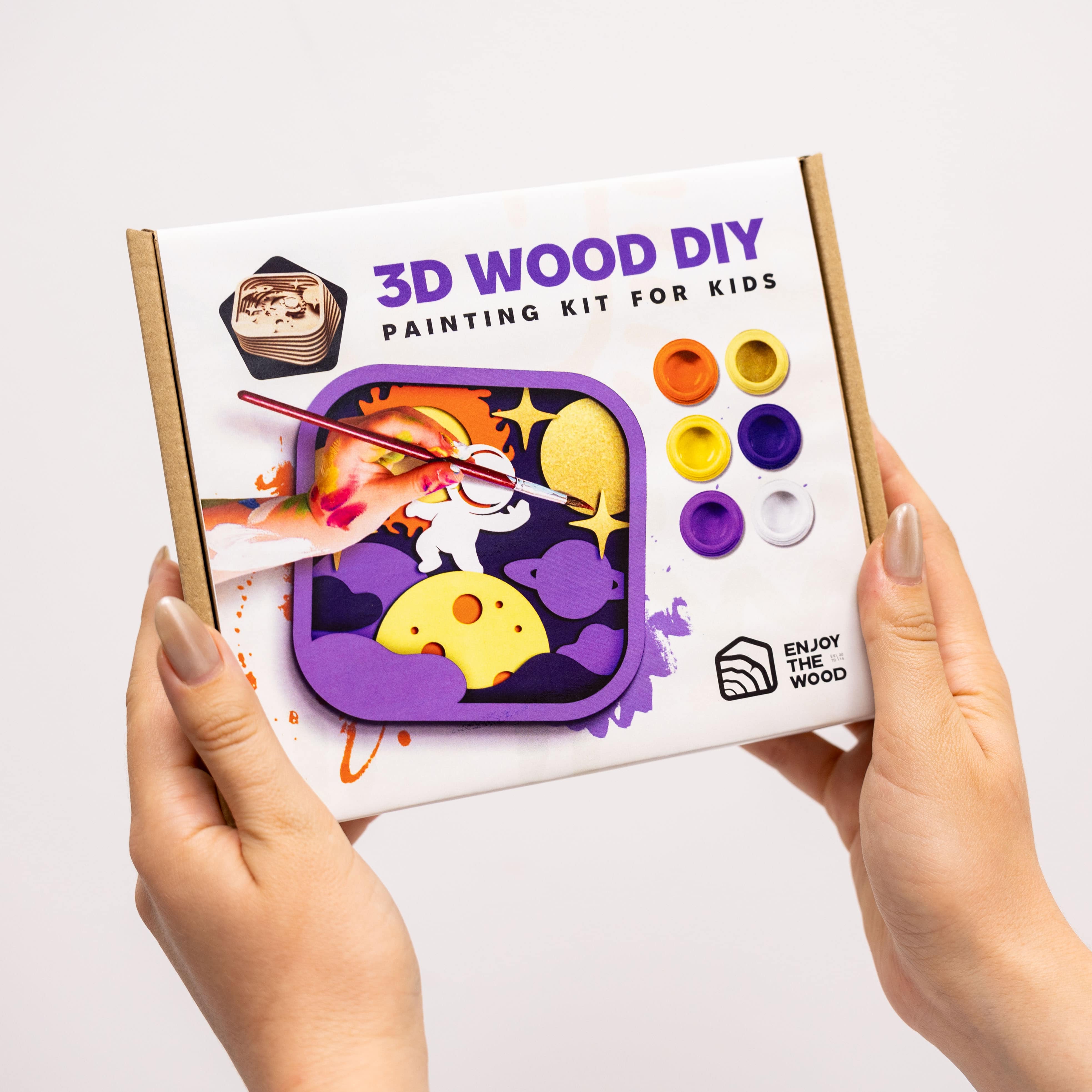 3D Wood DIY painting kit for kids held by hands on a white background