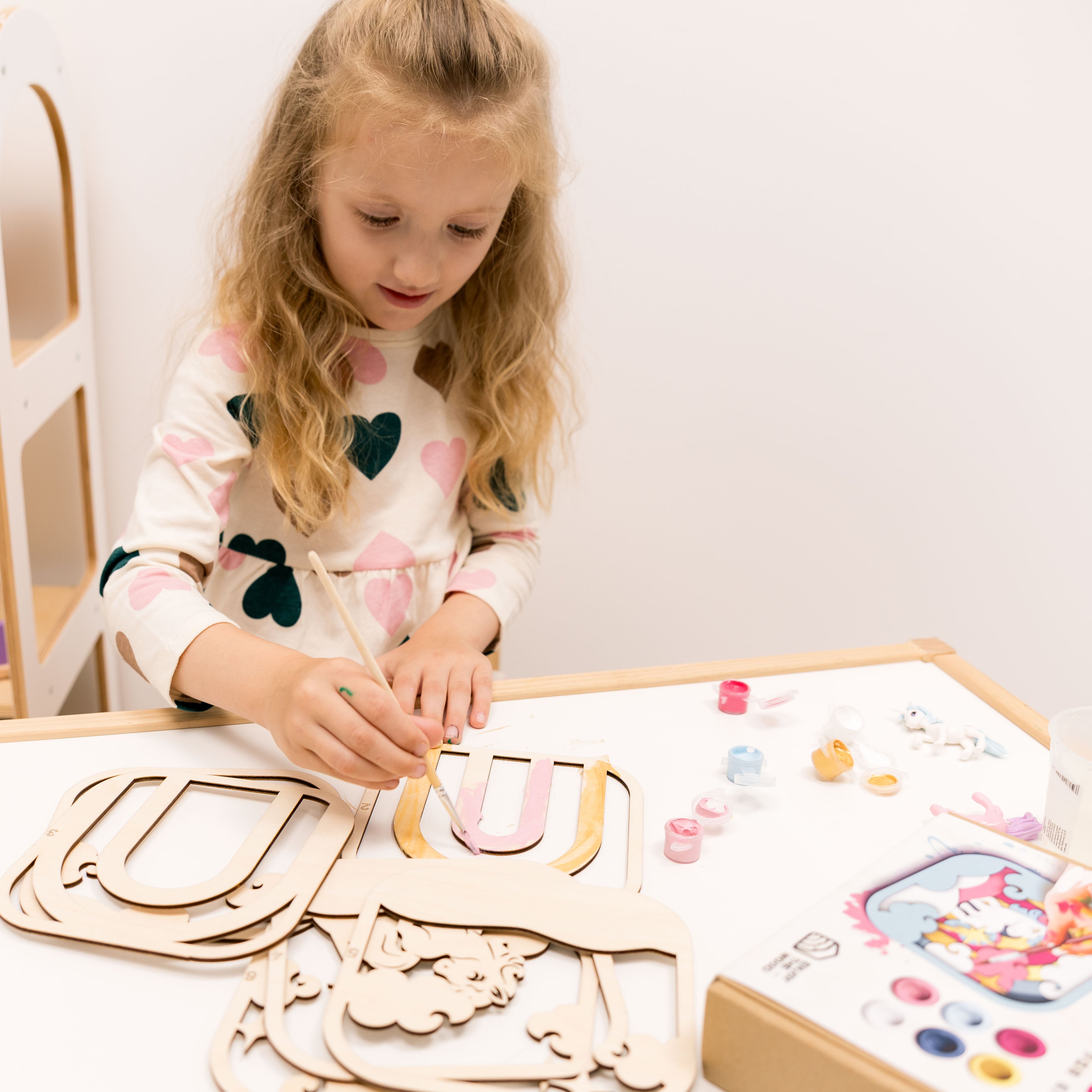 Young girl playing with wooden letters and colorful toys on a table.