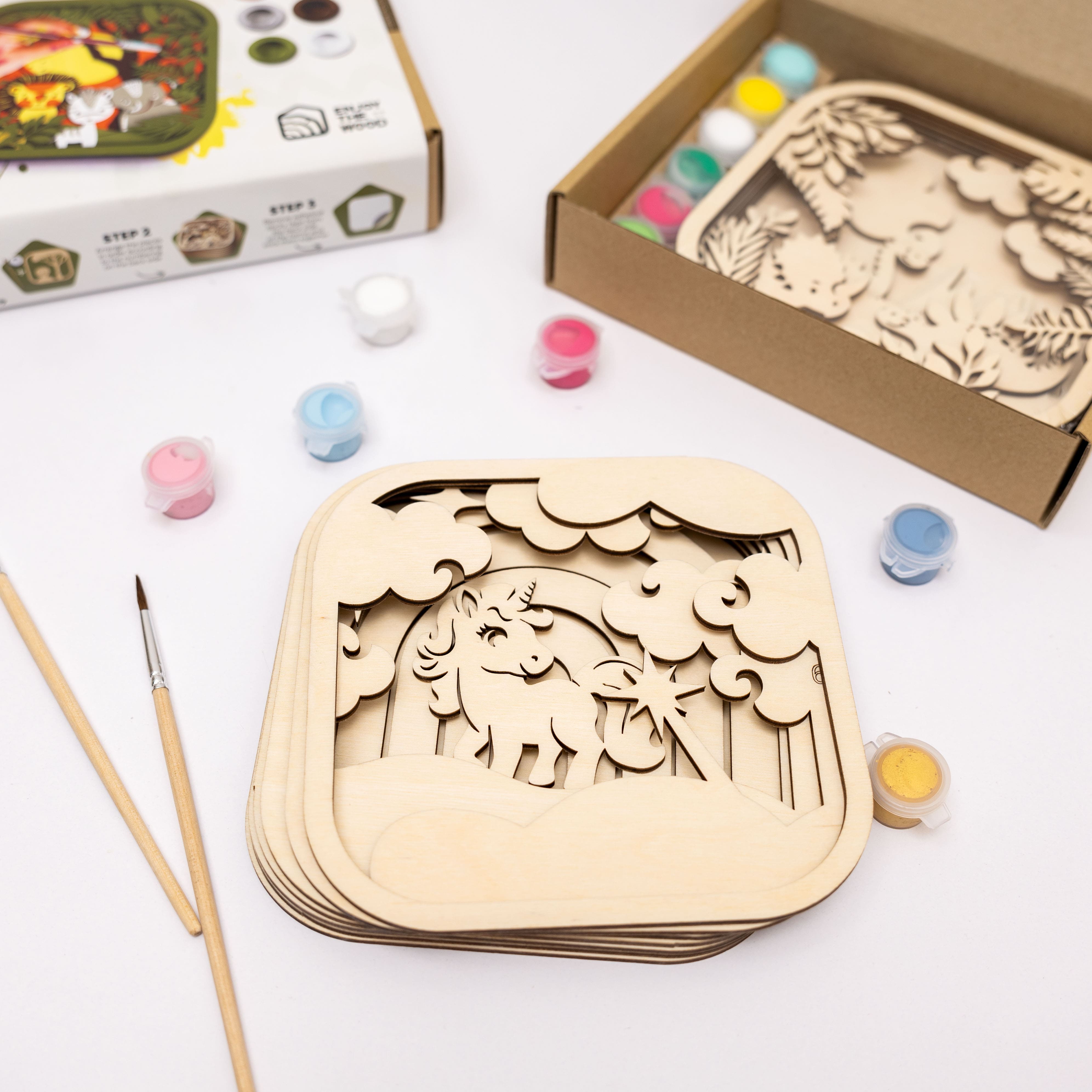 Wooden craft kits with paint cans and brushes on a white surface