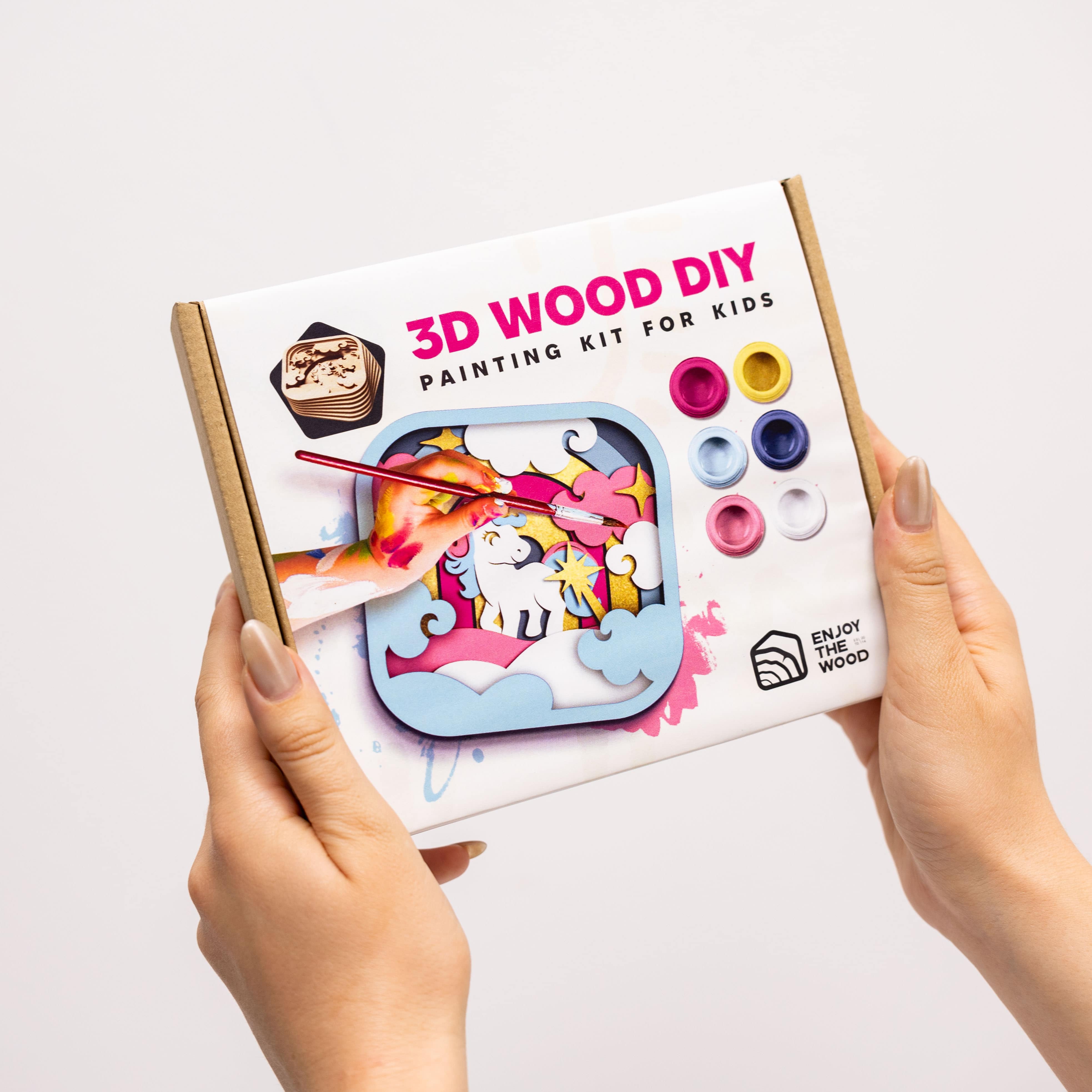 3D Wood DIY painting kit for kids held by hands on a light background