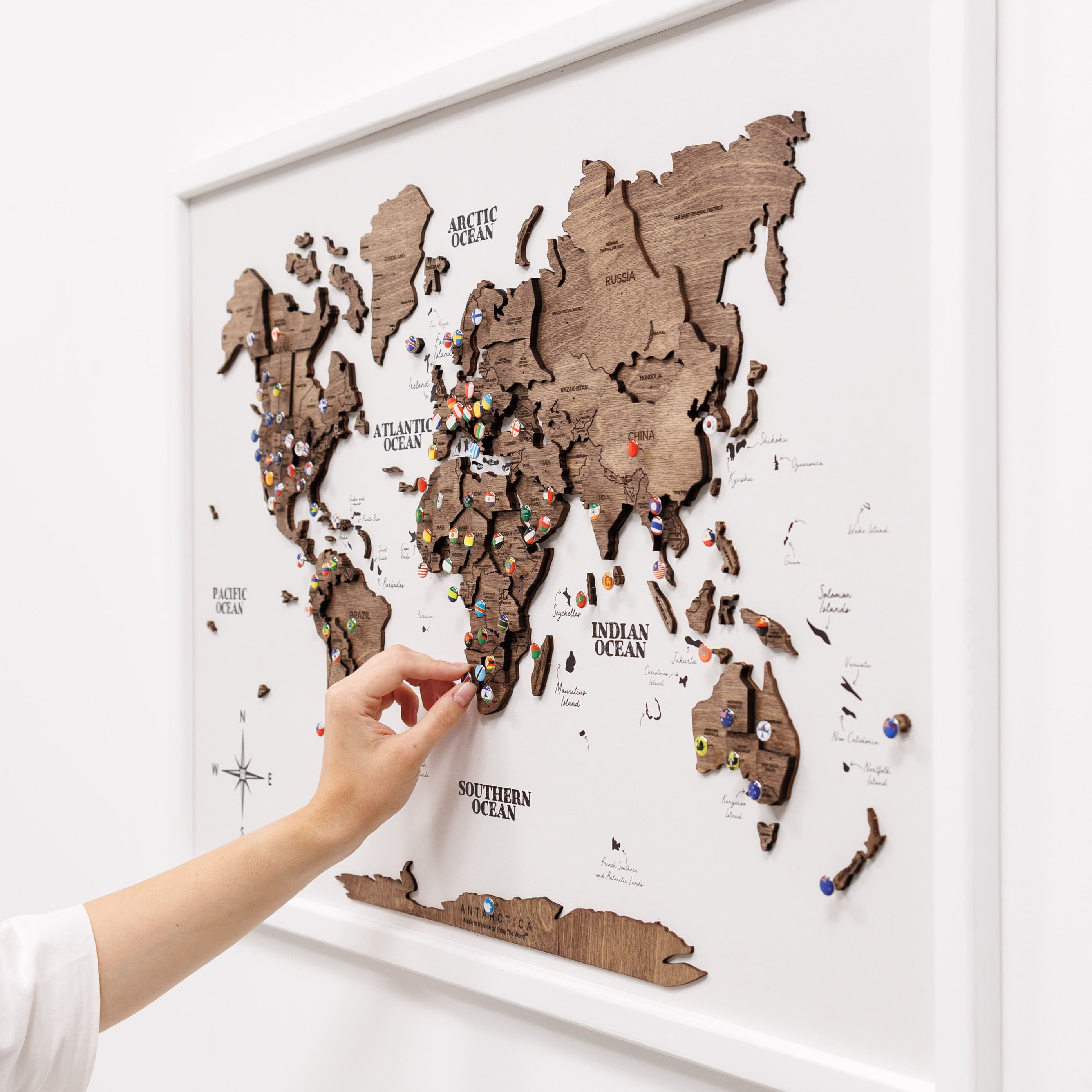 Wooden world map with pins on a white wall
