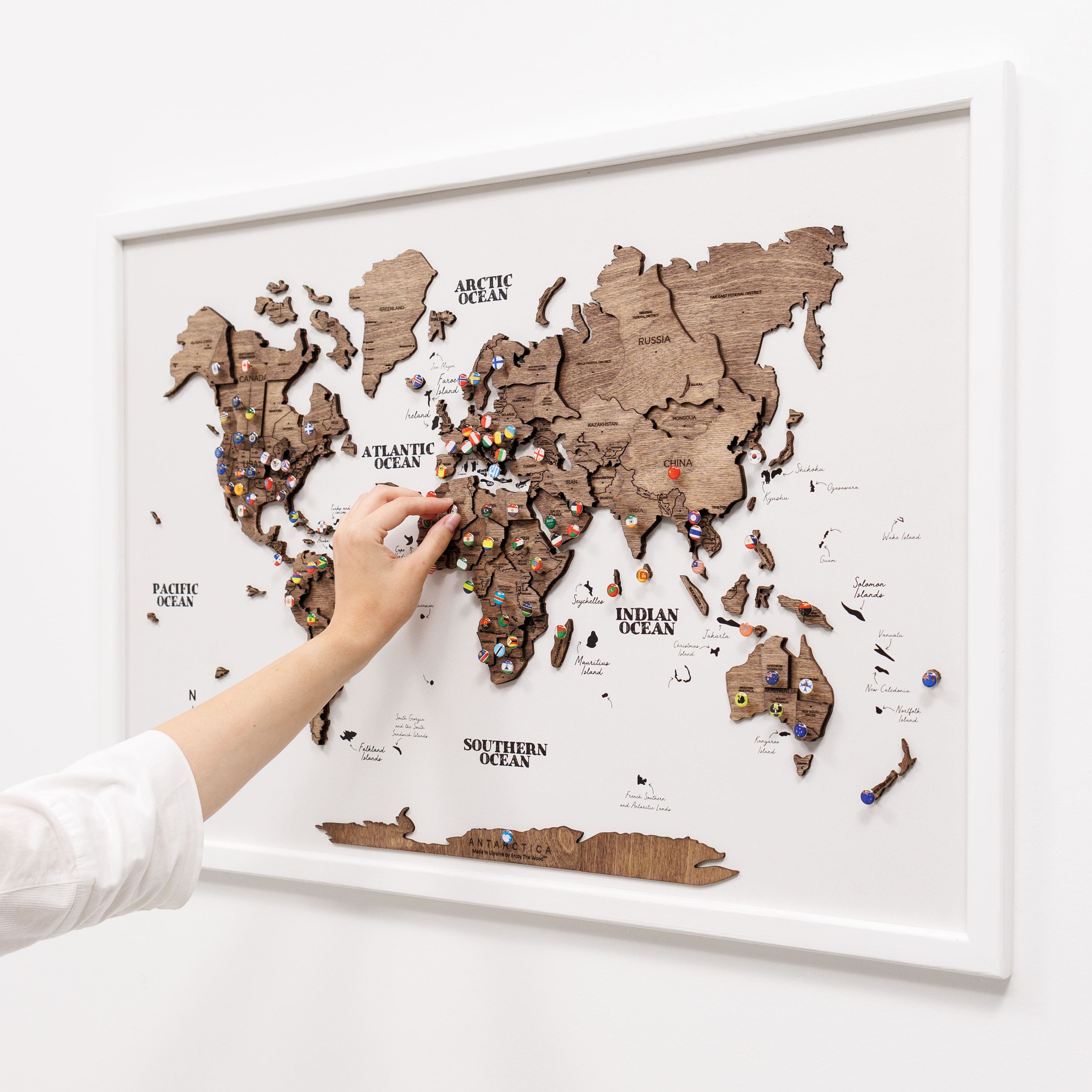 Wooden world map with pins on a white background