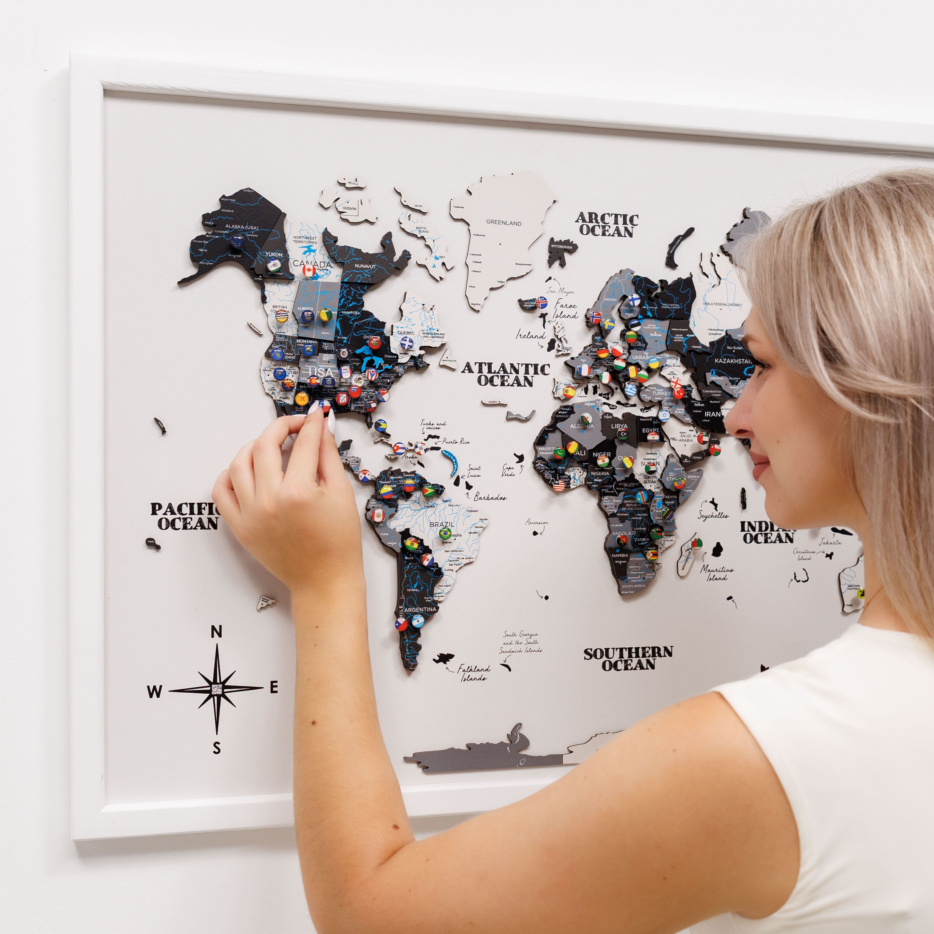 Woman interacting with a world map poster on a white wall