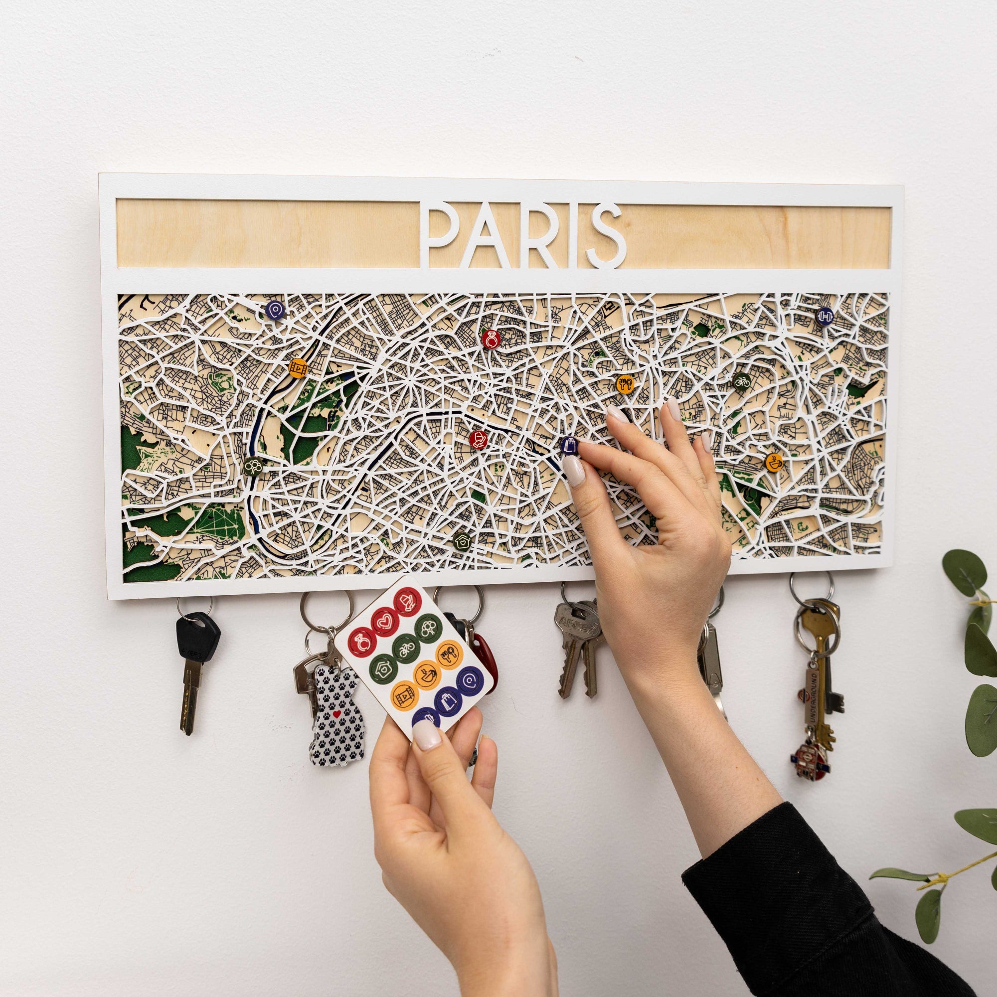 Map of Paris with keychains attached on a white wall