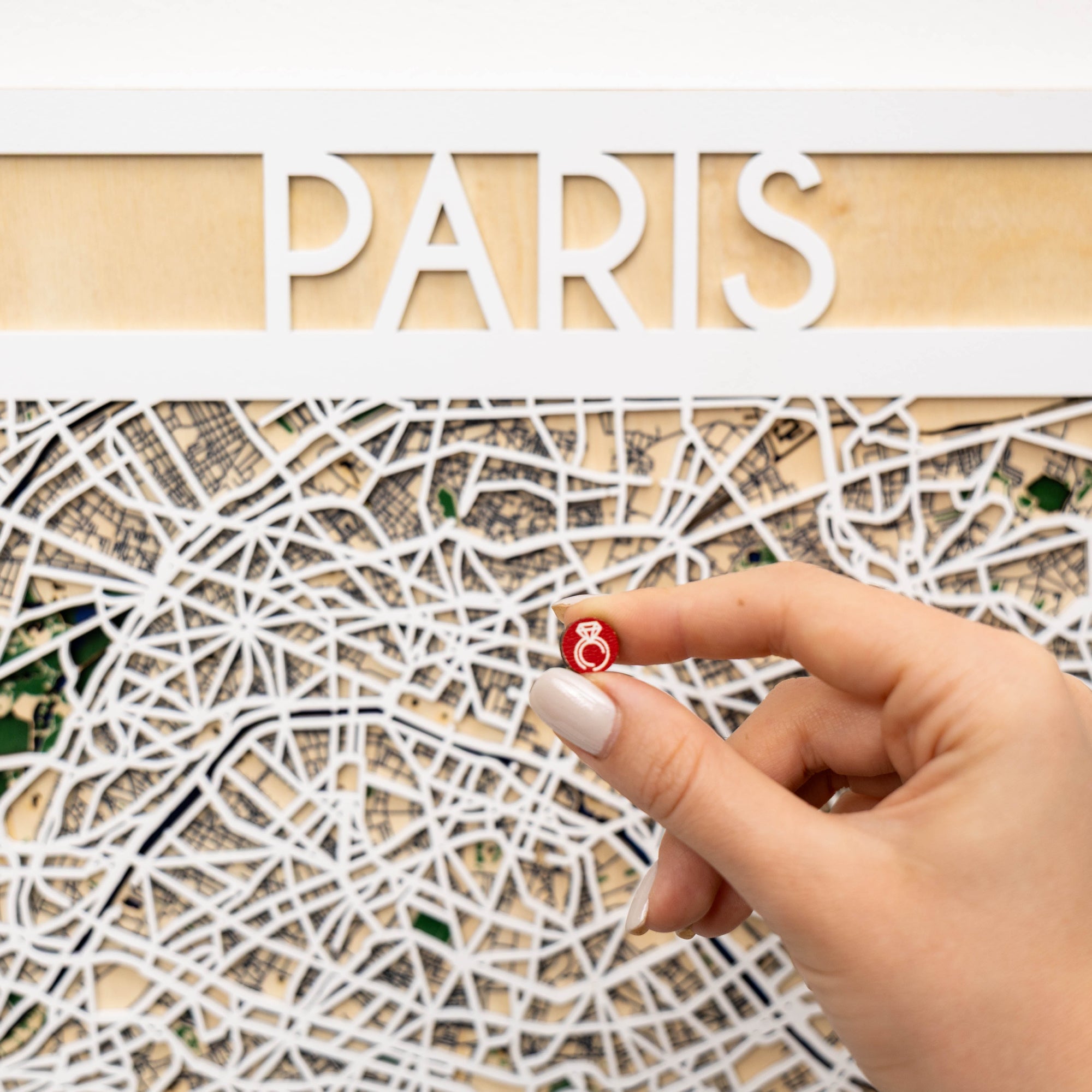 Hand with a red pin on a map of Paris
