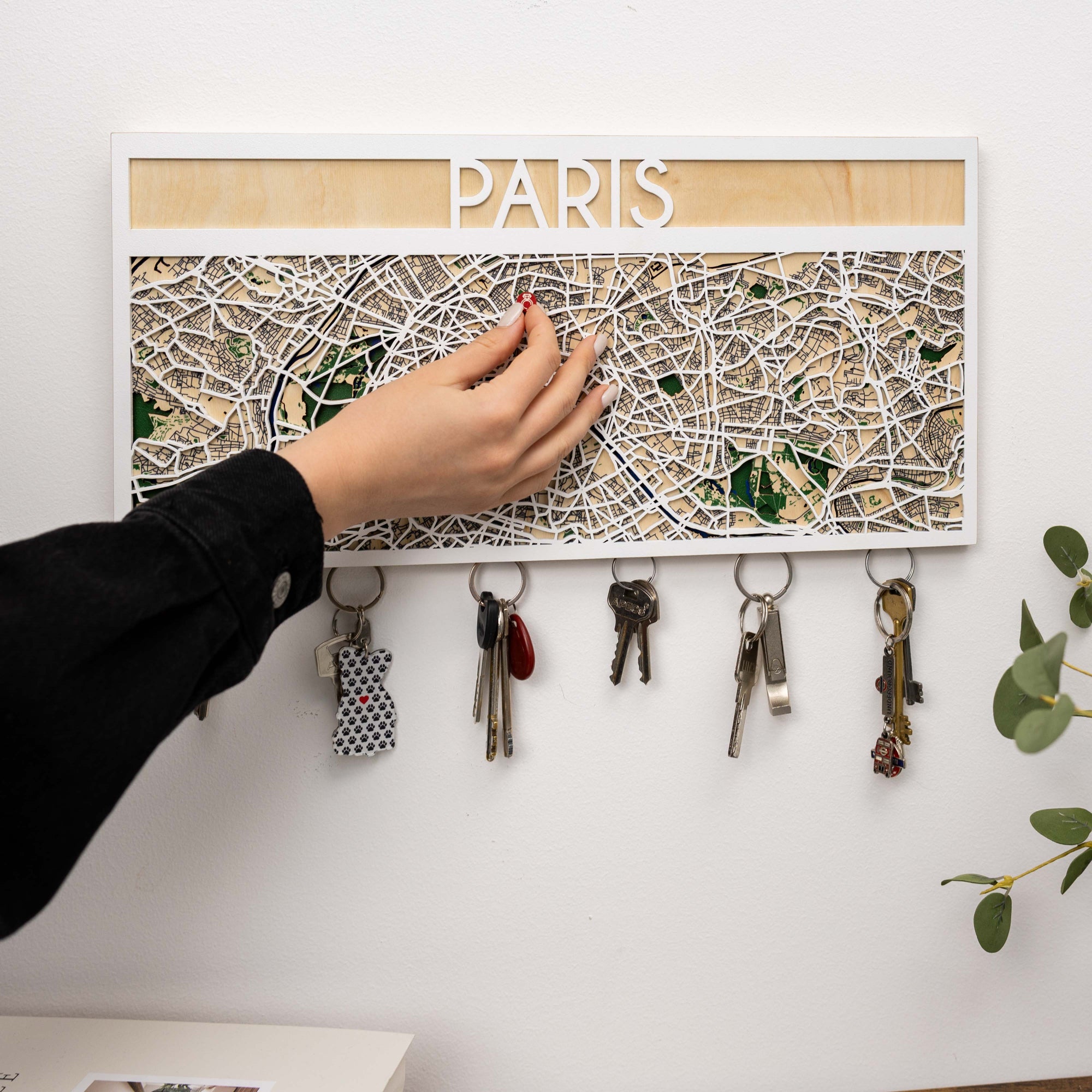 Key holder with a map of Paris and keys attached, on a white wall.