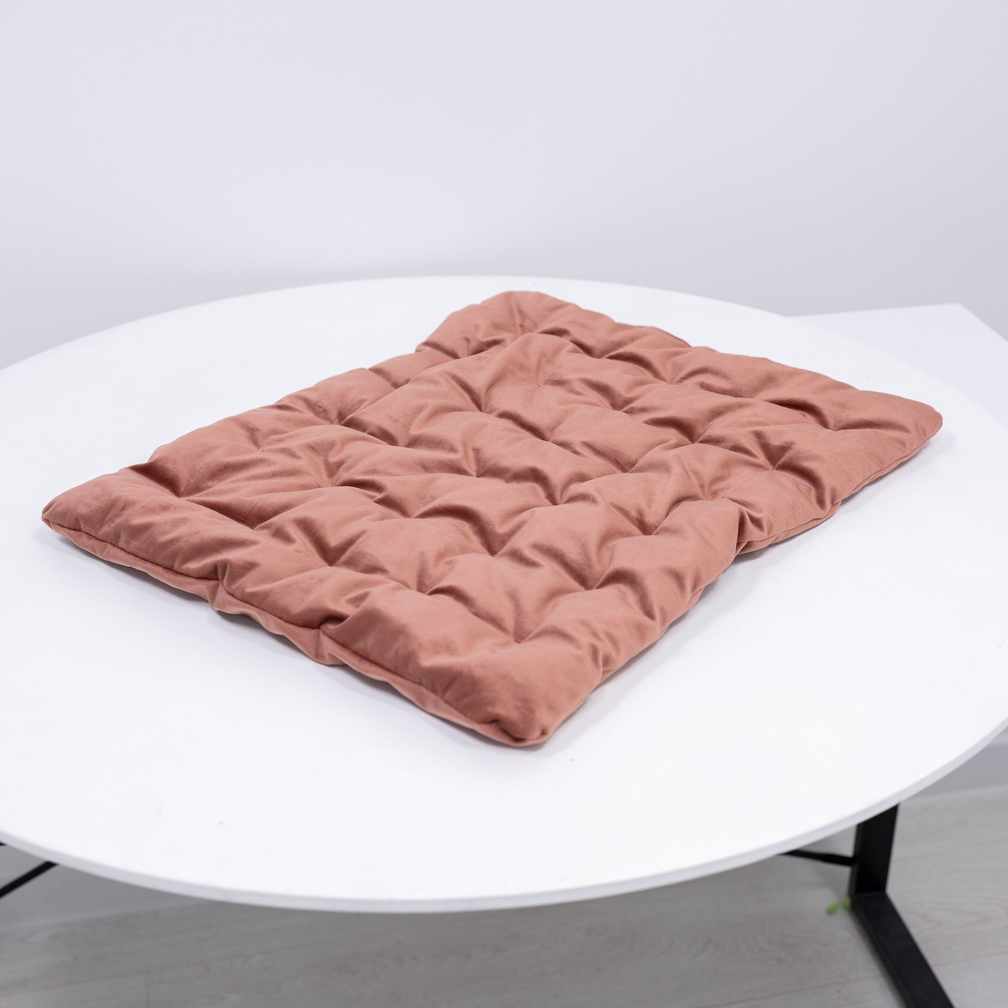 Pink quilted mat on a white round table against a light gray background