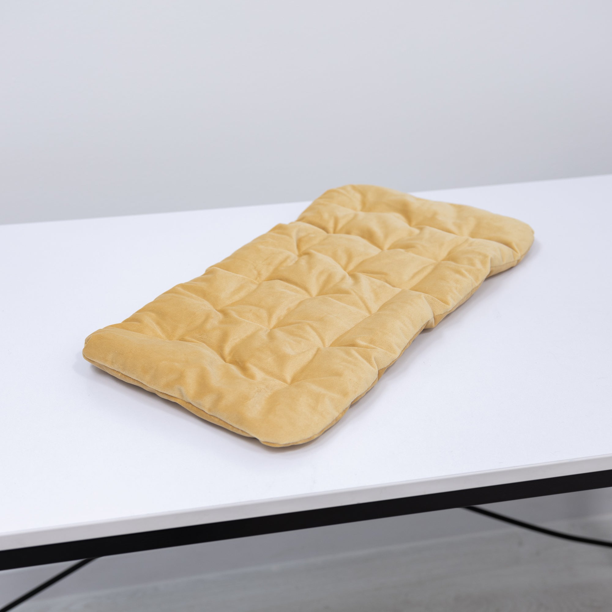 Beige quilted mat on a white surface with a light gray background