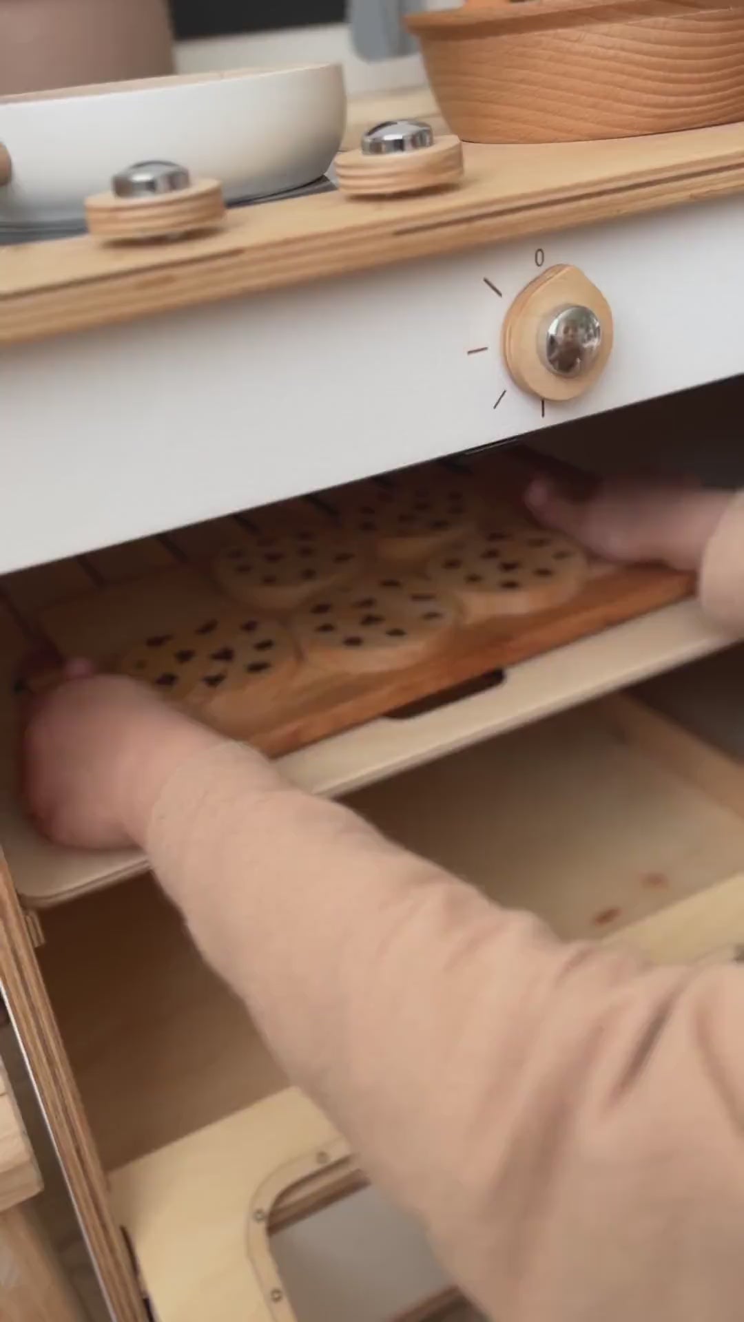 Child playing with wooden toy kitchen oven and cookies.