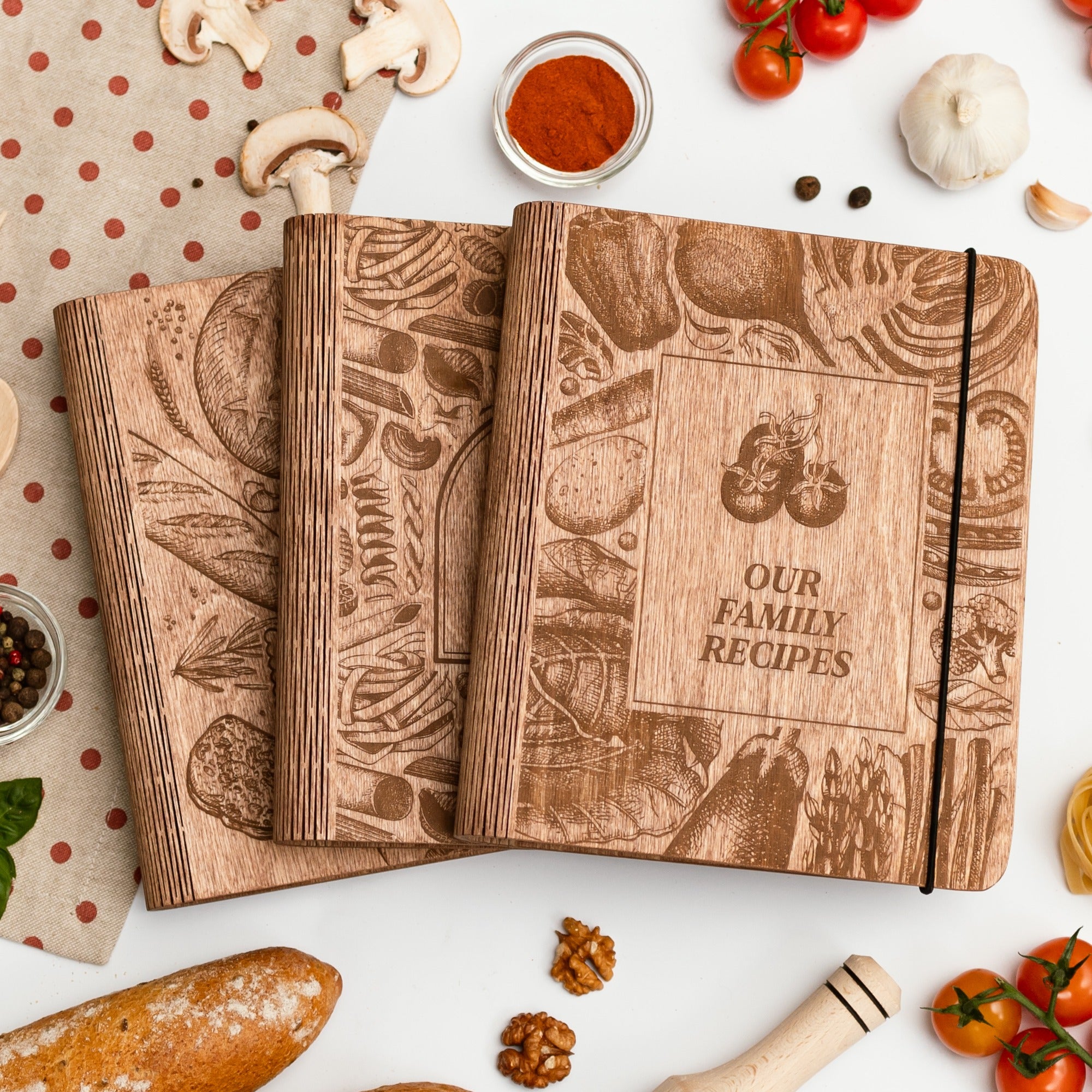 Wooden recipe books with 'Our Family Recipes' on a table with kitchen items.